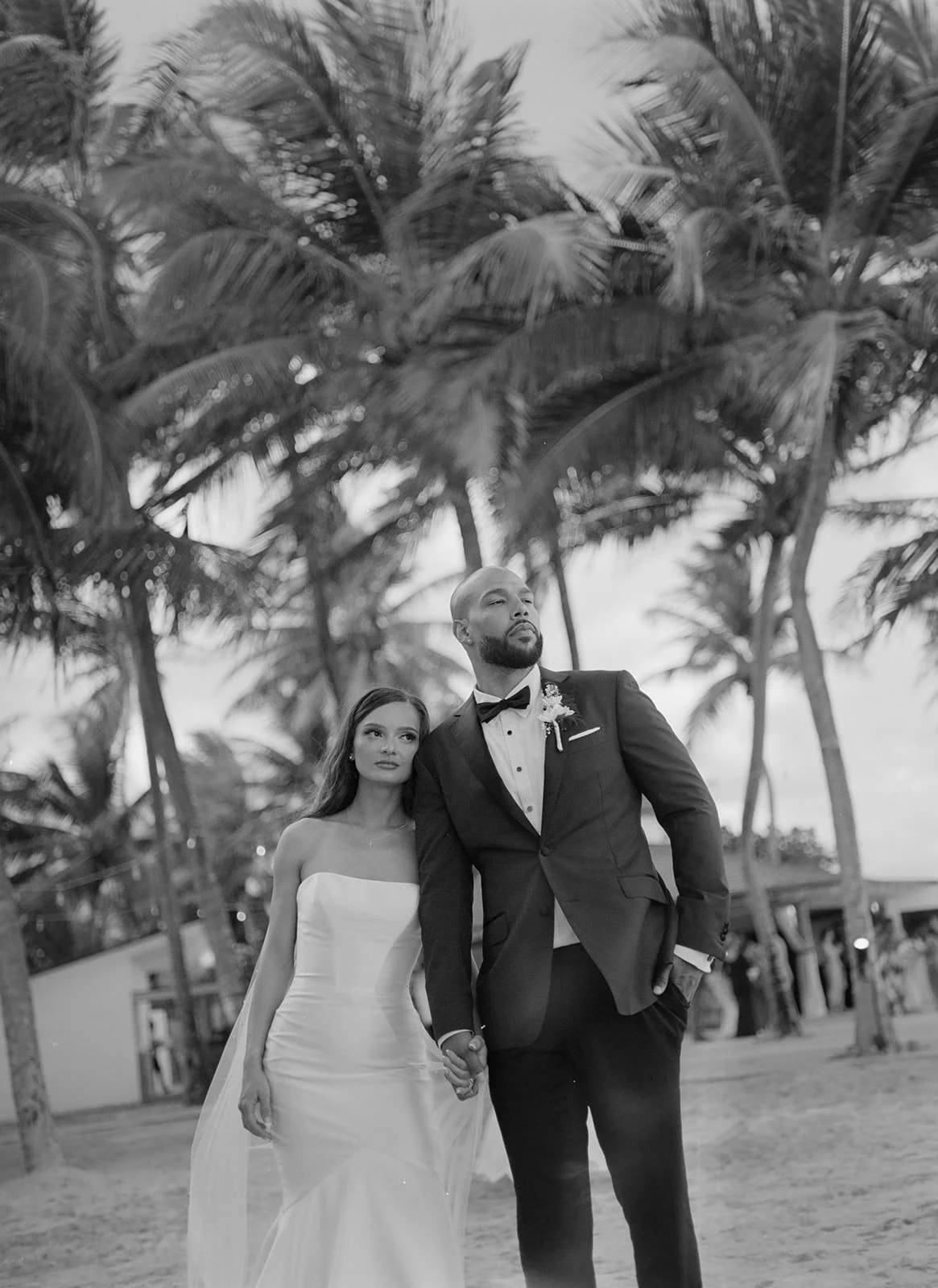 Black and white photo of the bride and groom walking together on the St. Lucia beach beneath palm trees