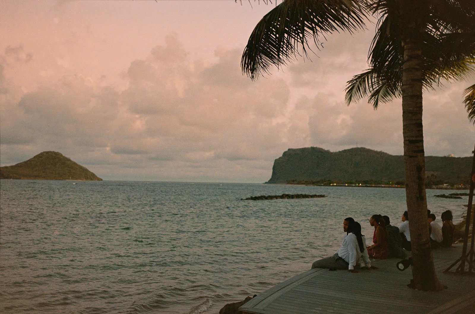 Guests sitting on the seawall at dusk overlooking a small island off the St. Lucia coastline