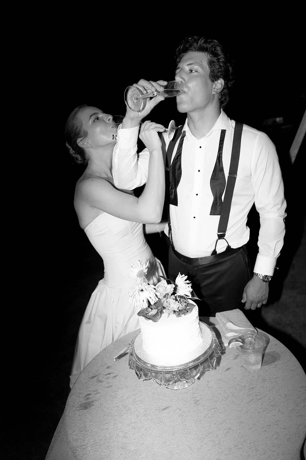 Black and white photo of the bride and groom sharing a toast beside their wedding cake at the Islamorada, Florida Keys destination wedding