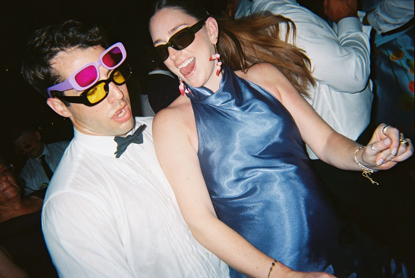 Guests dancing together wearing colorful sunglasses at the nighttime reception for this Islamorada, Florida Keys destination wedding