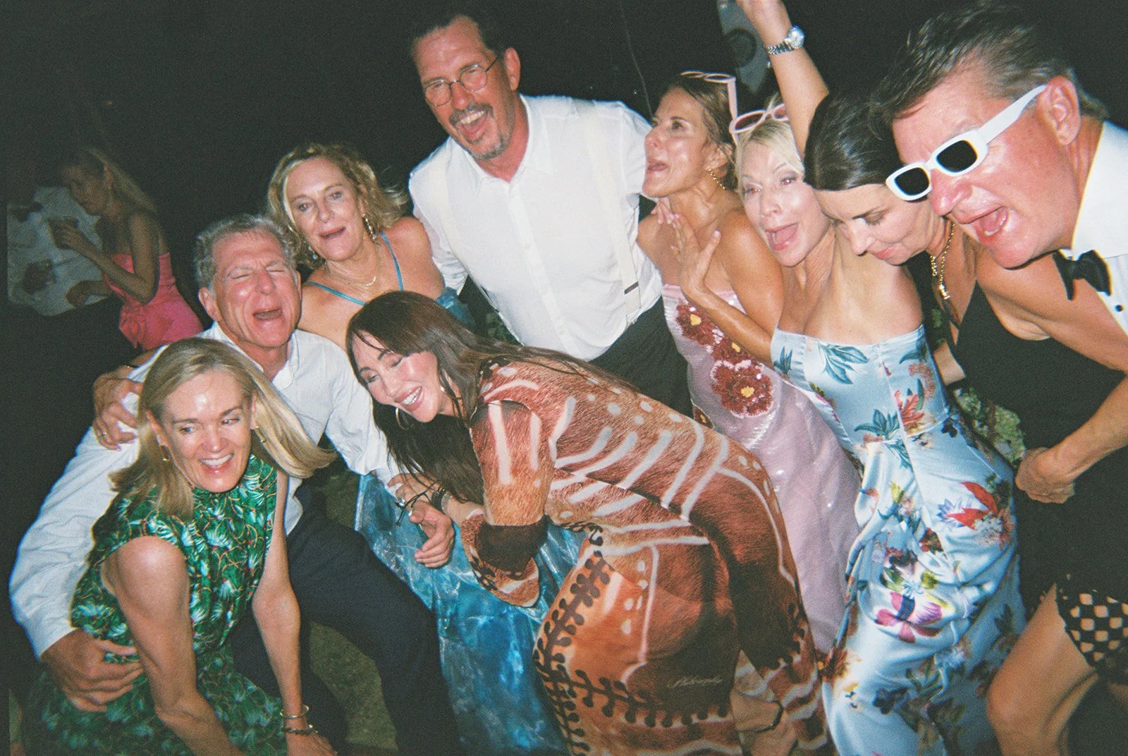 Group of wedding guests laughing together in sunglasses at the nighttime celebration for this Islamorada, Florida Keys destination wedding