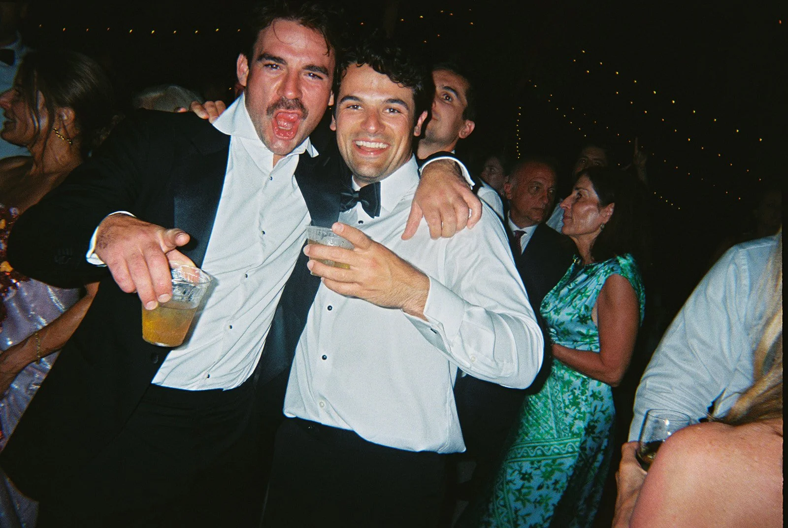 Groomsmen in tuxedos posing candidly with drinks at the nighttime reception for this Islamorada, Florida Keys destination wedding