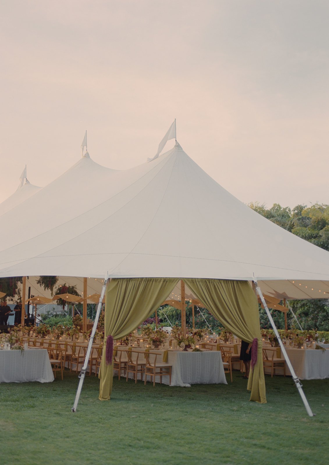 White sailcloth reception tent with string lights and dining tables set up among palm trees at this Islamorada, Florida Keys destination wedding