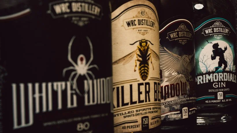 Close up of white widow, killer bee, shadow hawk, and primordials gin liquor bottles