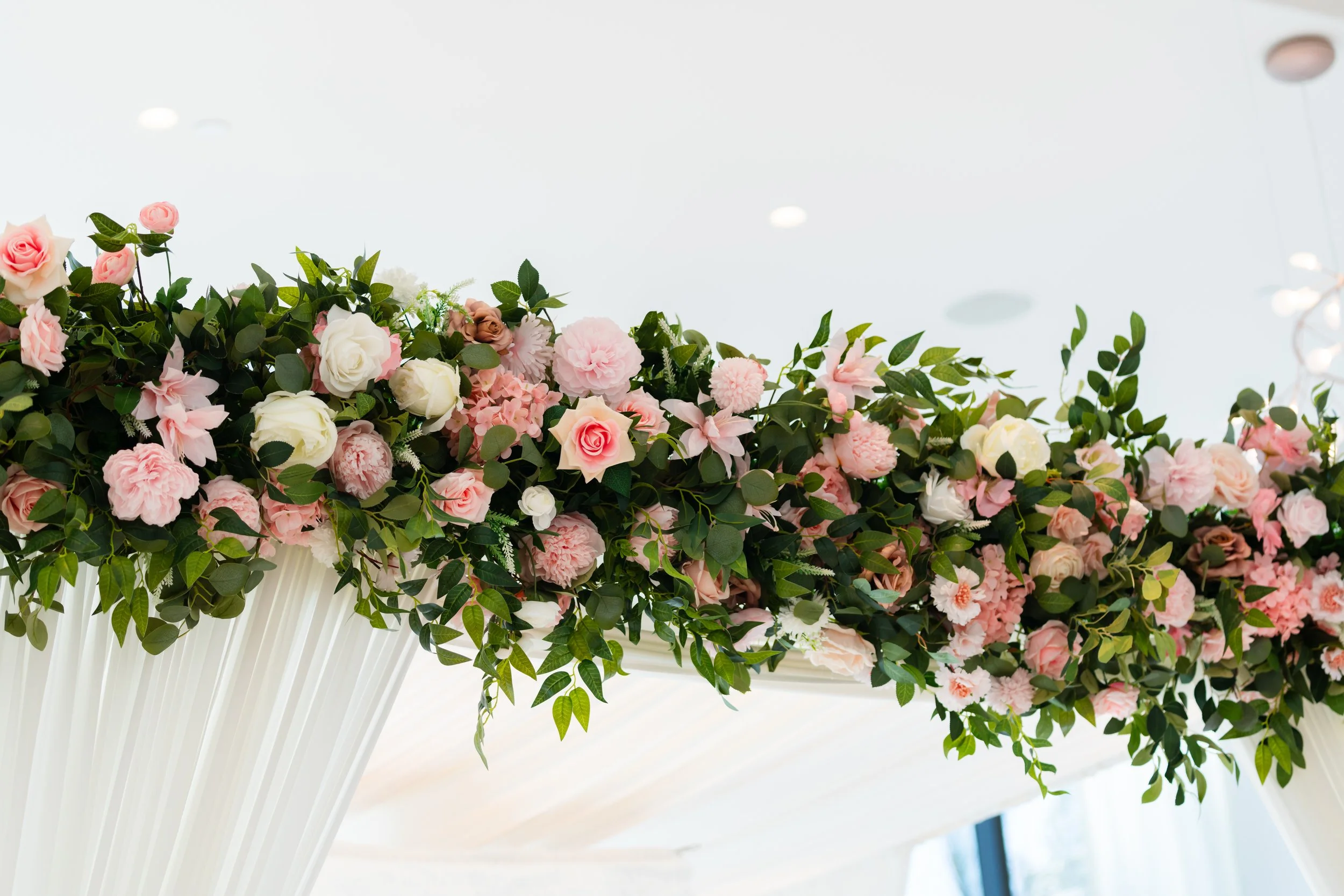 Decorative floral arrangement with pink and white roses, carnations, and greenery.