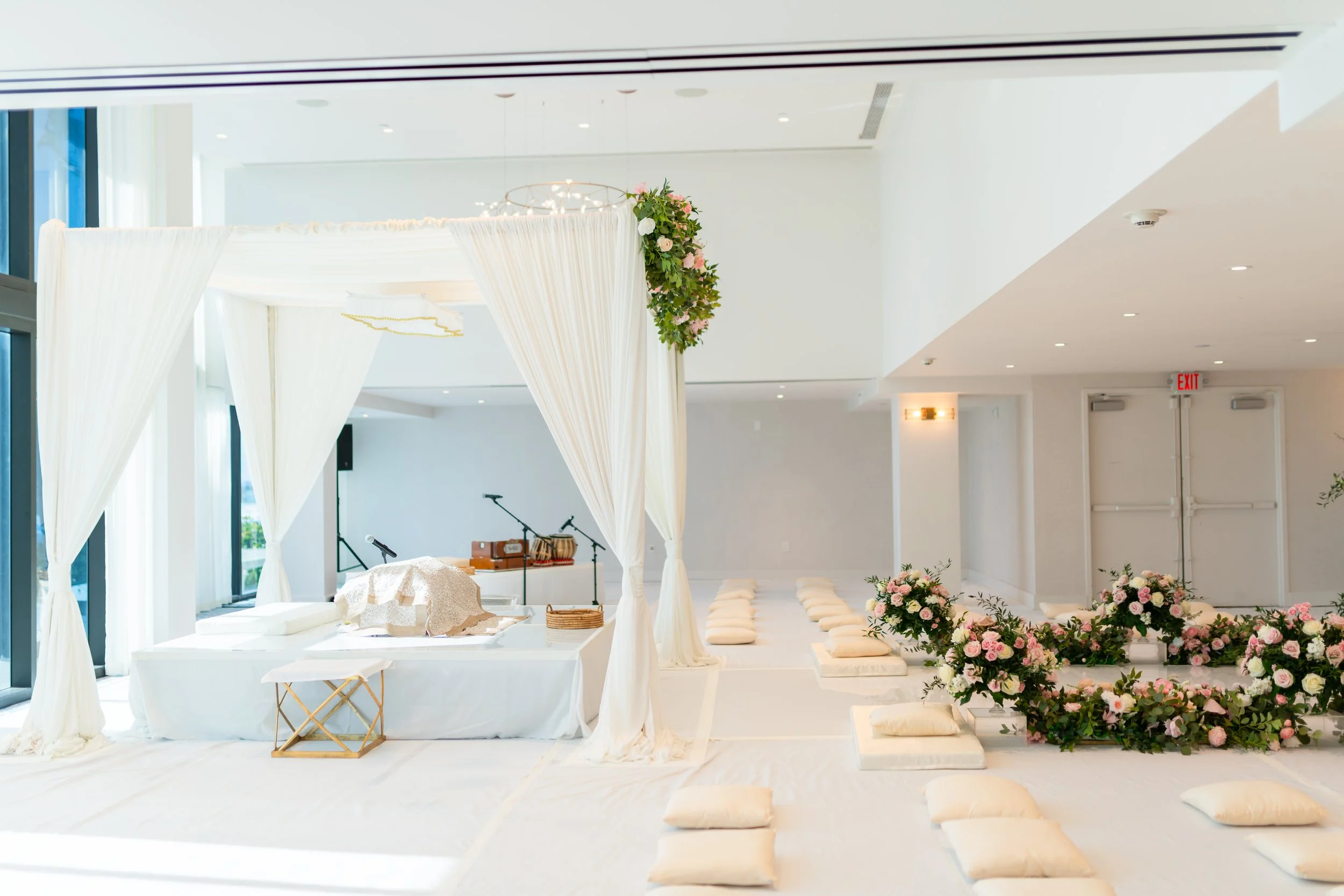 Wedding ceremony setup with a decorated arch, cushions for seating, and floral arrangements