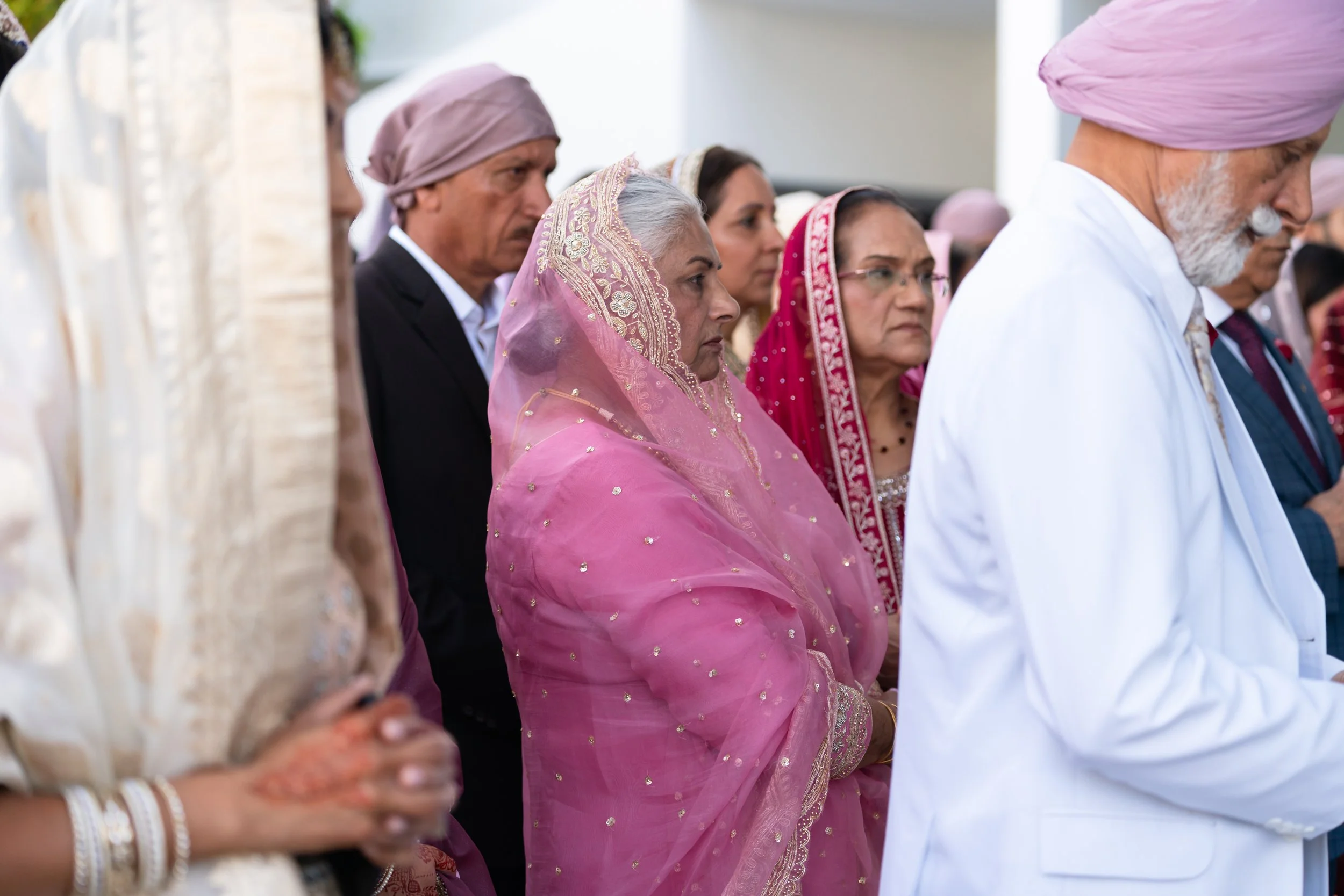Group of Indian people wearing traditional clothing, standing closely together during a prayer or ceremony.