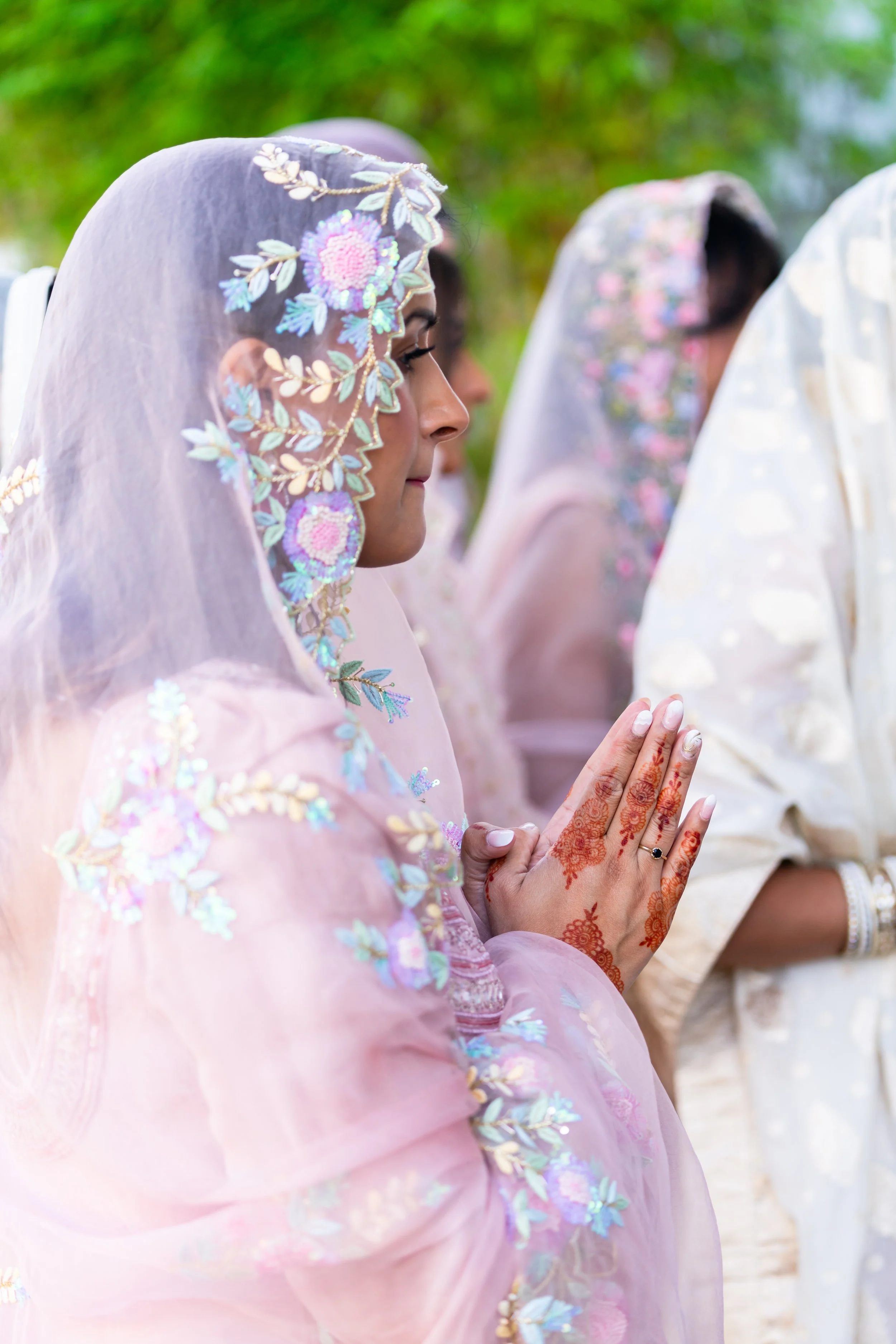 Women wearing traditional Indian dresses and praying outdoor with hands pressed together.