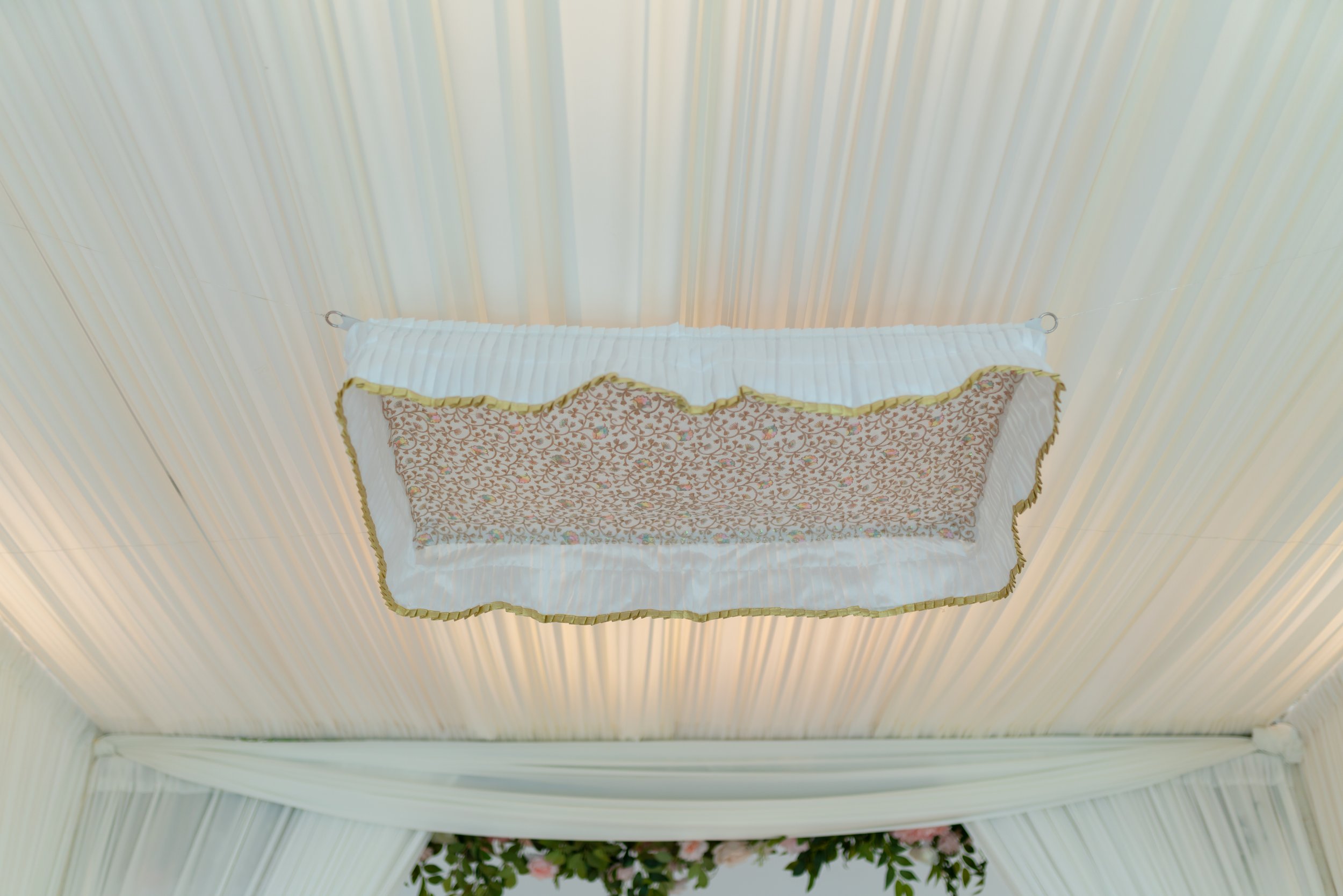 Ceiling with decorative fabric hanging, floral arrangement below.