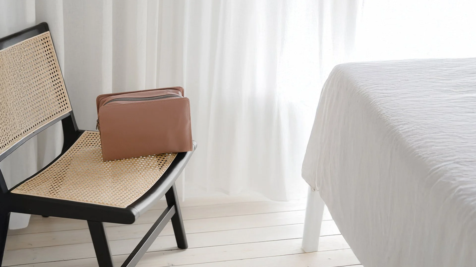 V&M SPA Dusty Rose leather toiletry bag on rattan chair in soft natural light — handmade Sydney ECO leather travel bag