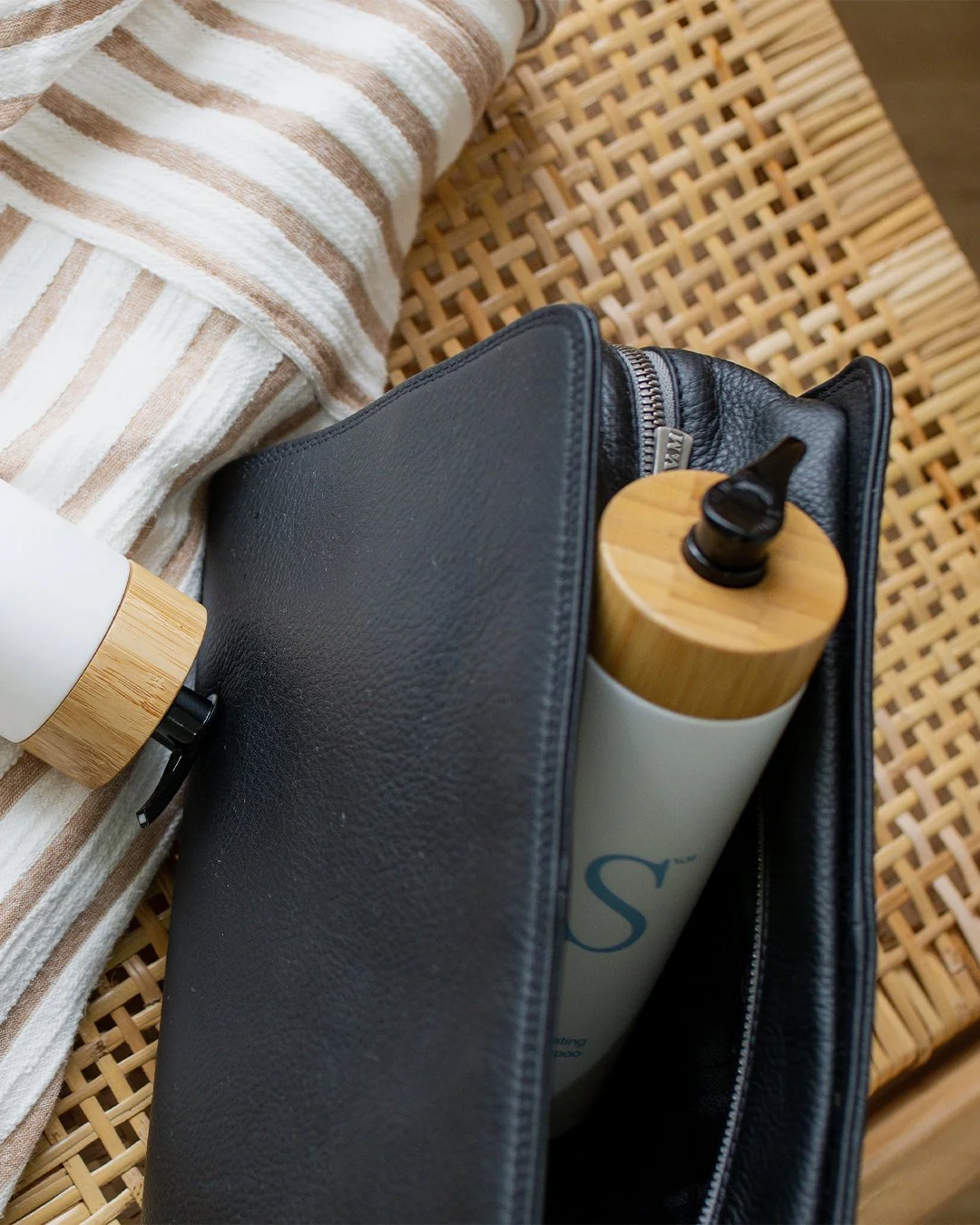 V&M SPA black leather toiletry bag open with 60ml travel set products in side pocket — Australian made luxury travel hair and body care