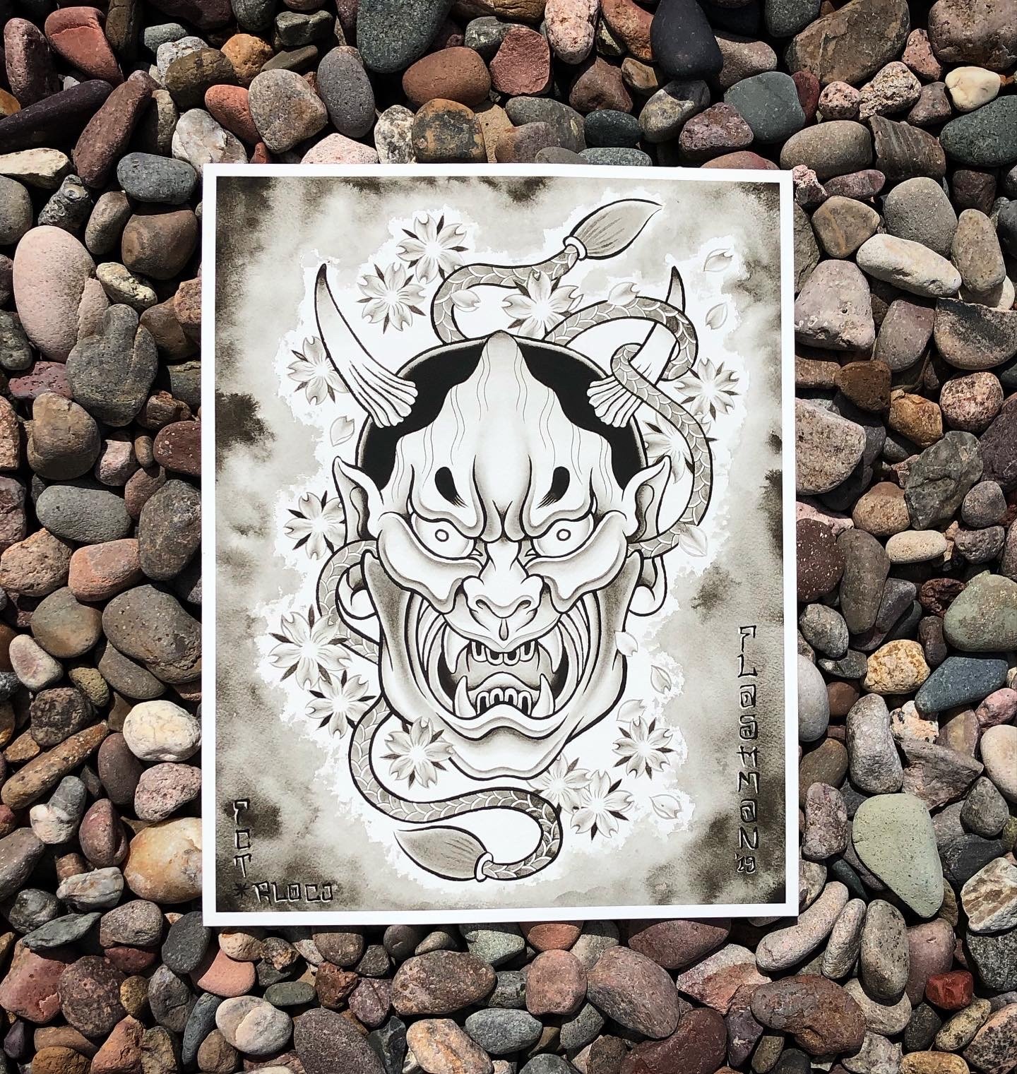 Black and white tattoo design of a menacing demon face with sharp teeth, prominent eyebrows, and pointed ears, surrounded by cherry blossoms and a coiled snake.
