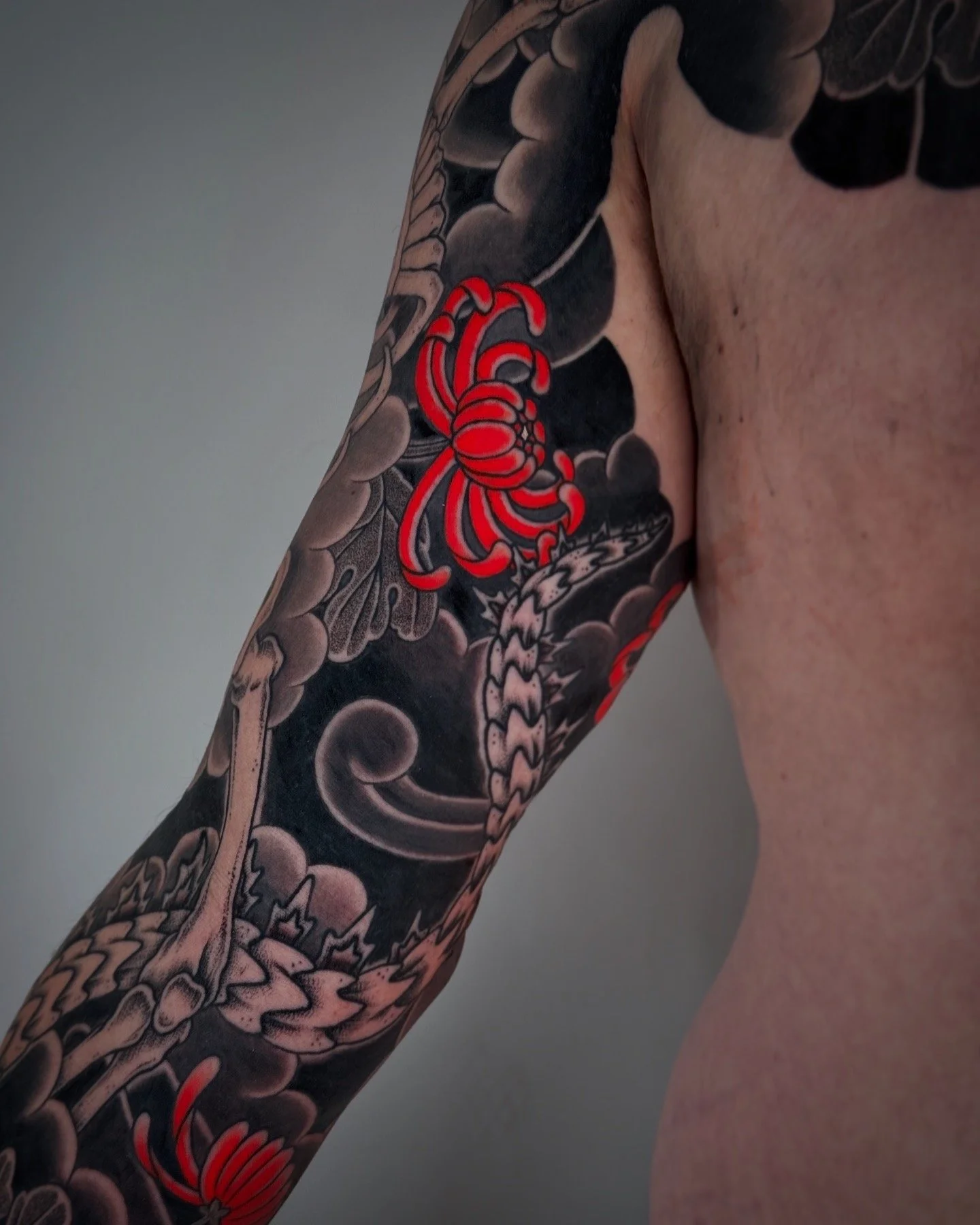 Tattoo of a red scorpion and a crab on a person's arm with dark background and cloud-like patterns.