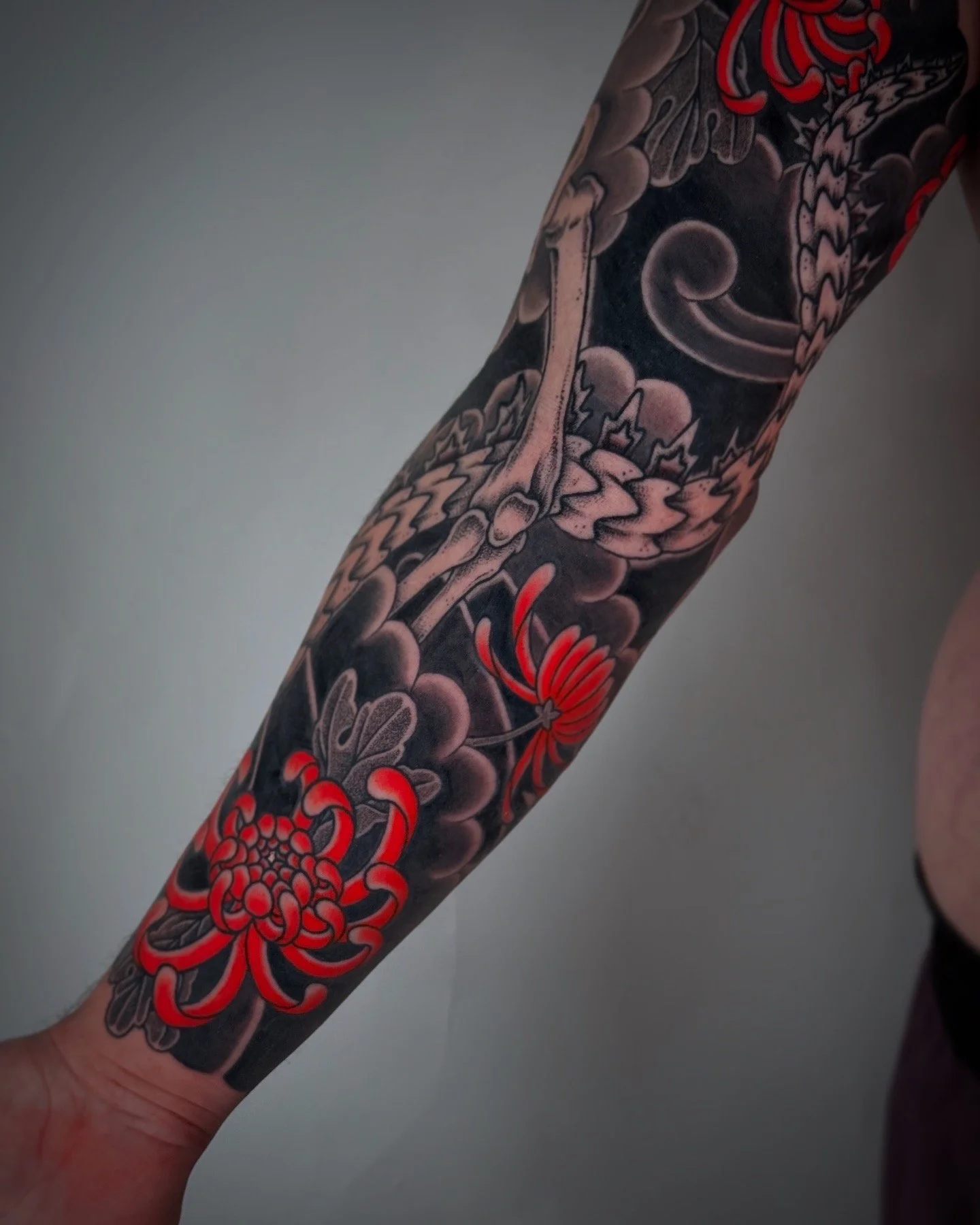 Tattoo of a dragon and flowers on a person's arm, with red accents.