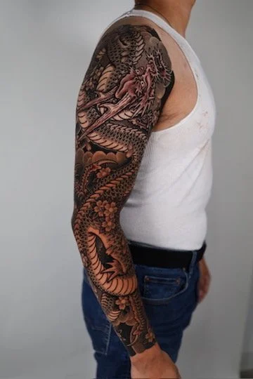 Tattoo sleeve featuring a detailed dragon design on a man's arm.