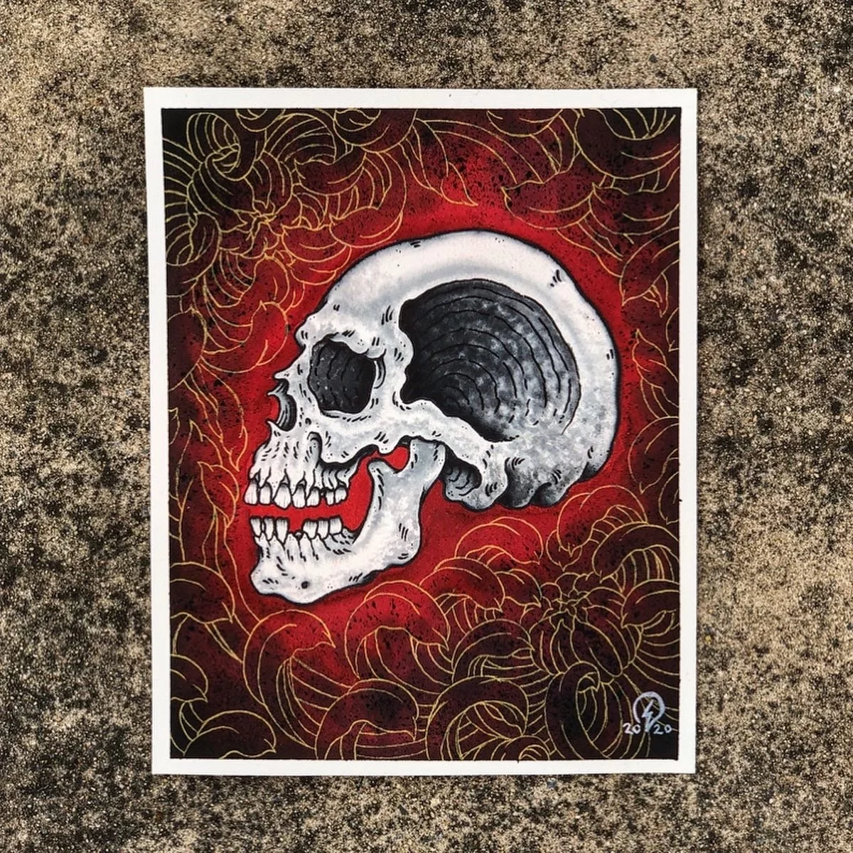 A detailed illustration of a human skull outlined in black and white, with a red background and gold leaf-like patterns surrounding it.