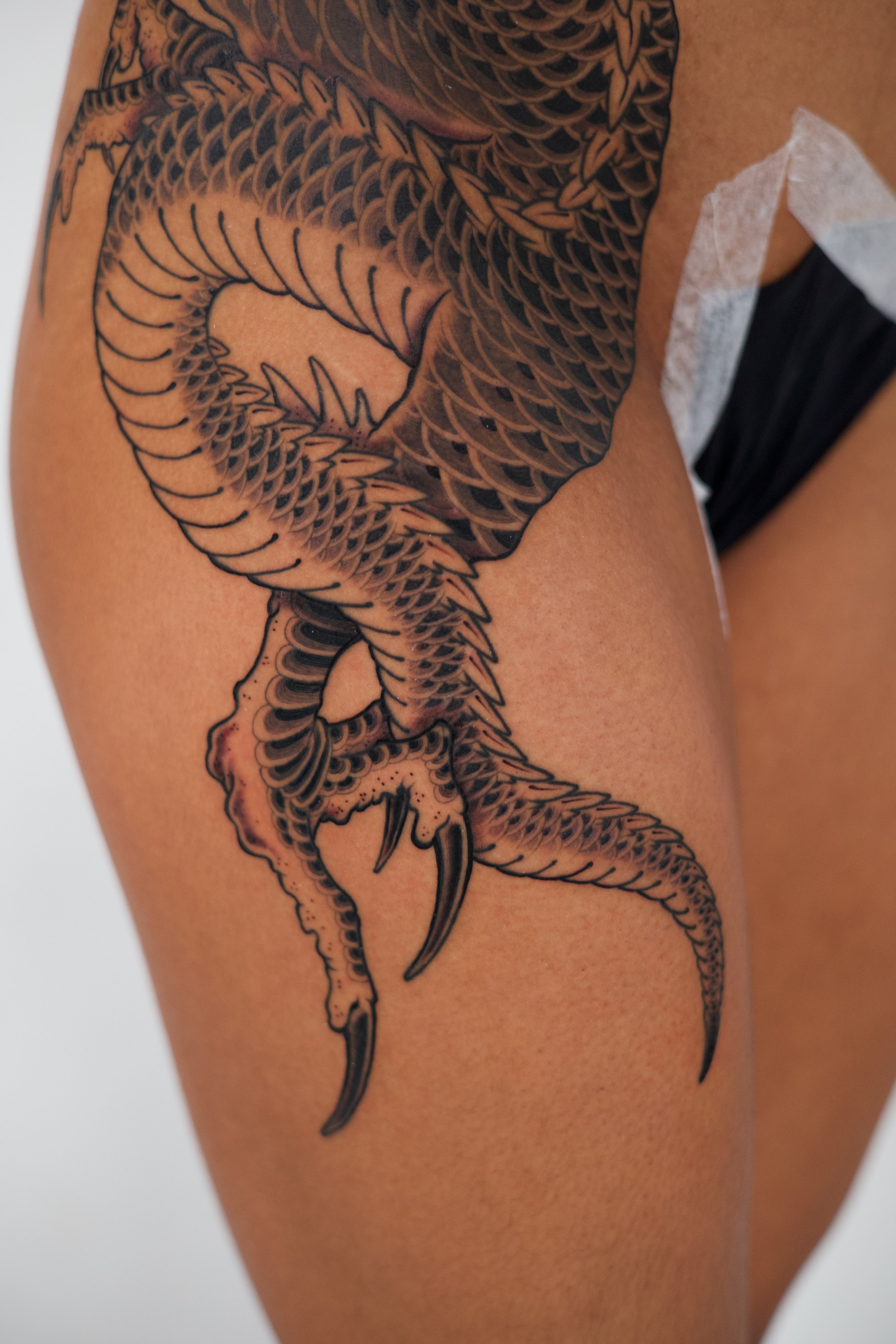 A detailed black and gray tattoo of a dragon on a person's upper arm and shoulder.