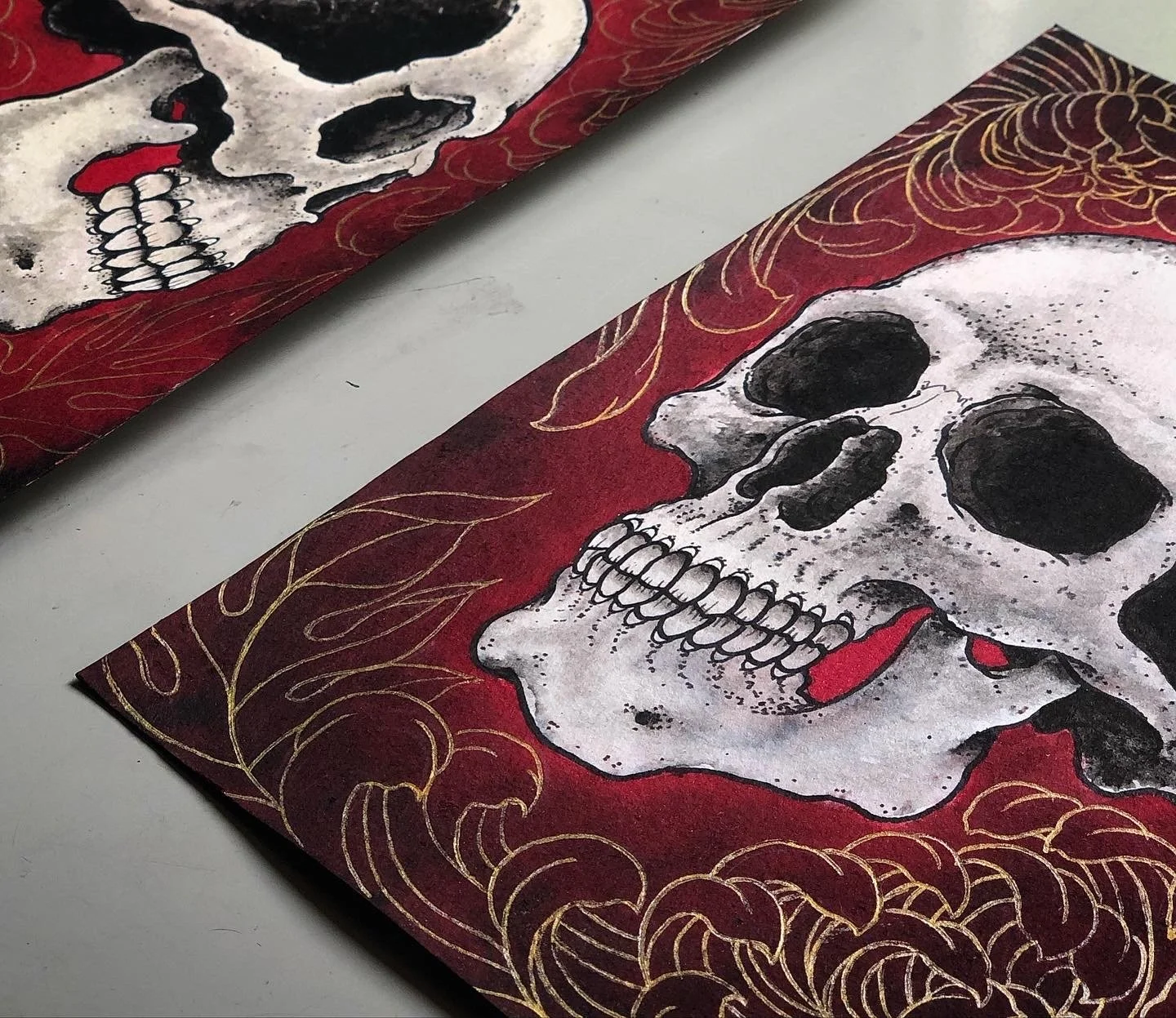 Artistic paintings of skulls on red backgrounds with gold decorative borders