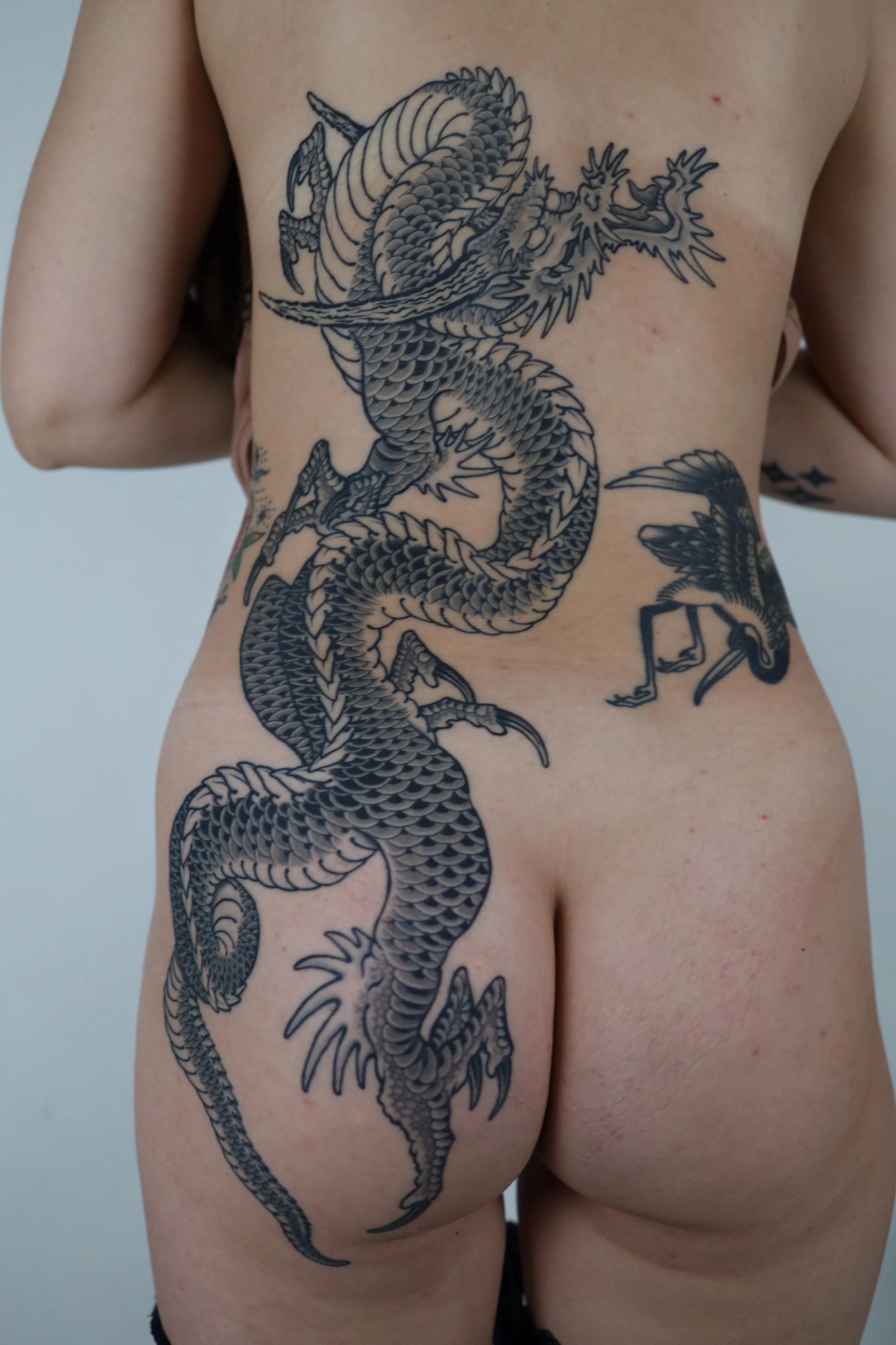 Back and butt tattoo of a large, black, detailed Chinese dragon.