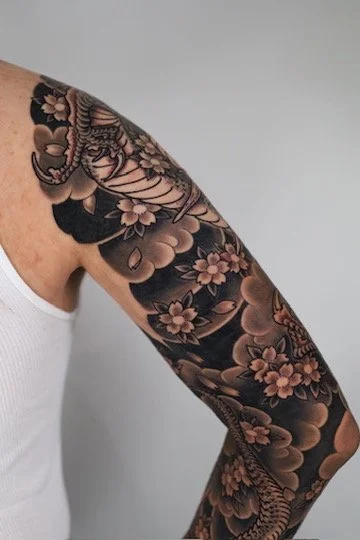 Tattooed arm with floral and dragon design.