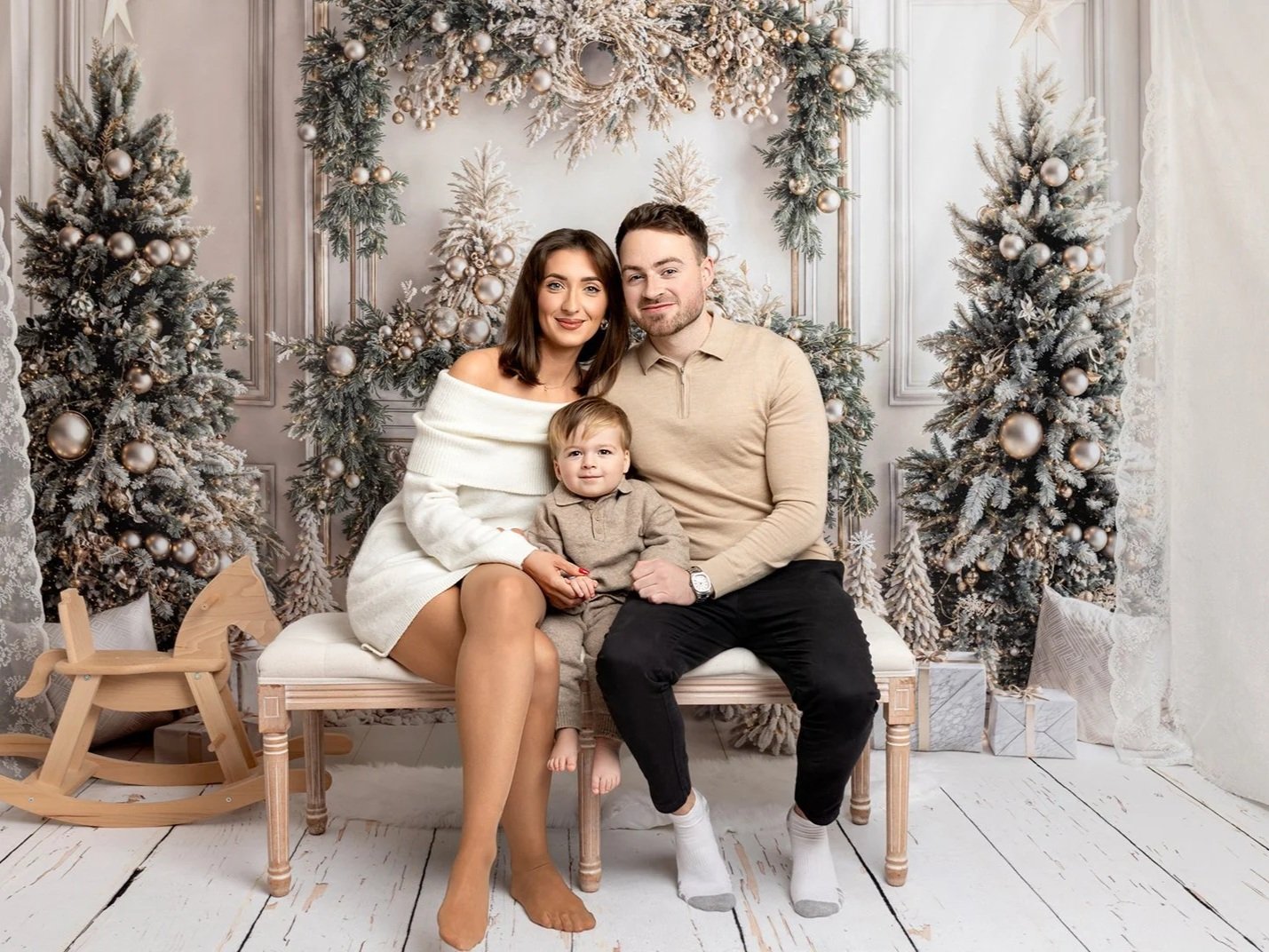 Mum, dad and their baby son sitting on a bench during their family Christmas photoshoot in Leeds