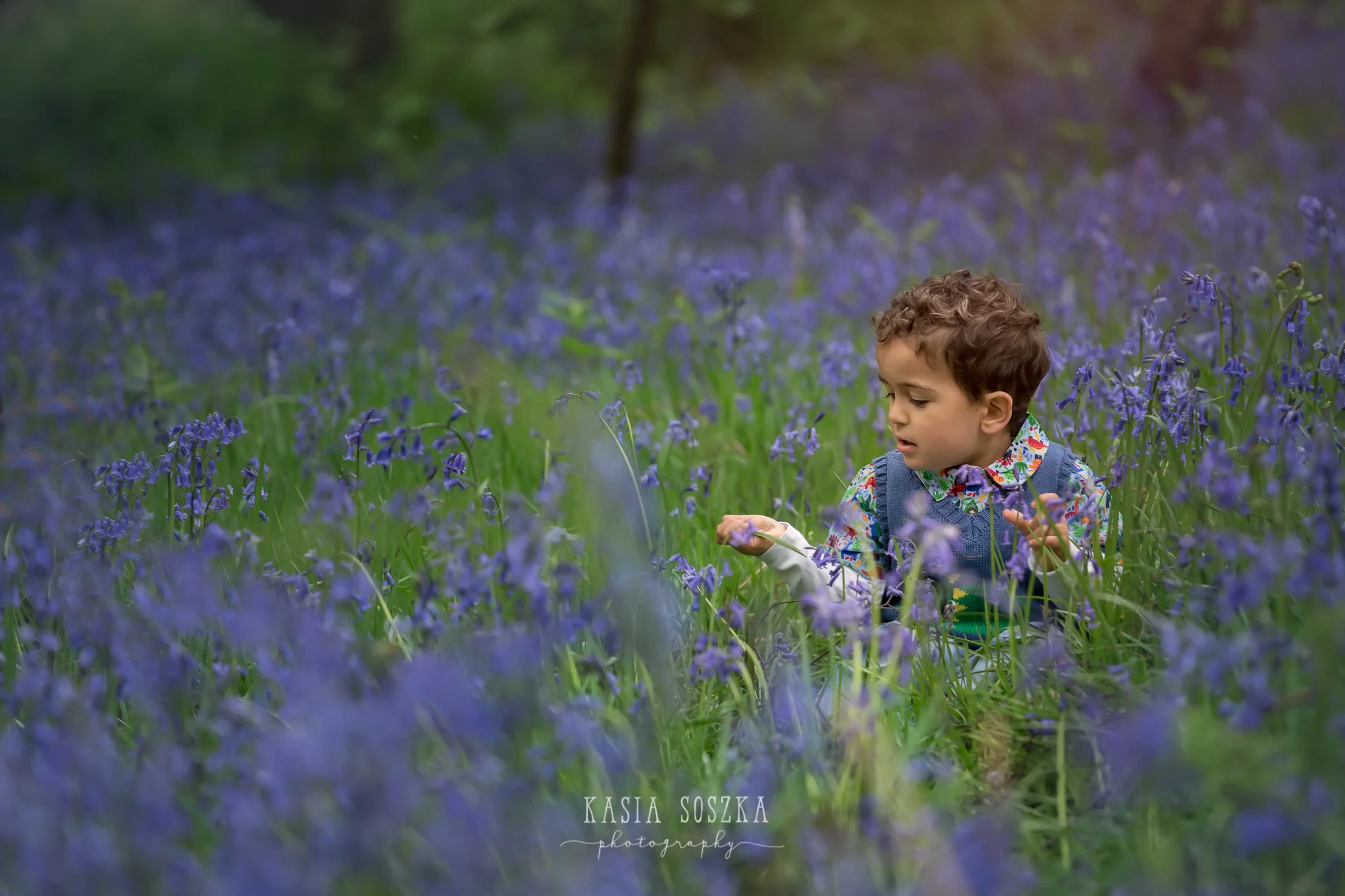 Leeds child photography: little boy with dark curly hair sitting in the middle of bluebell patch