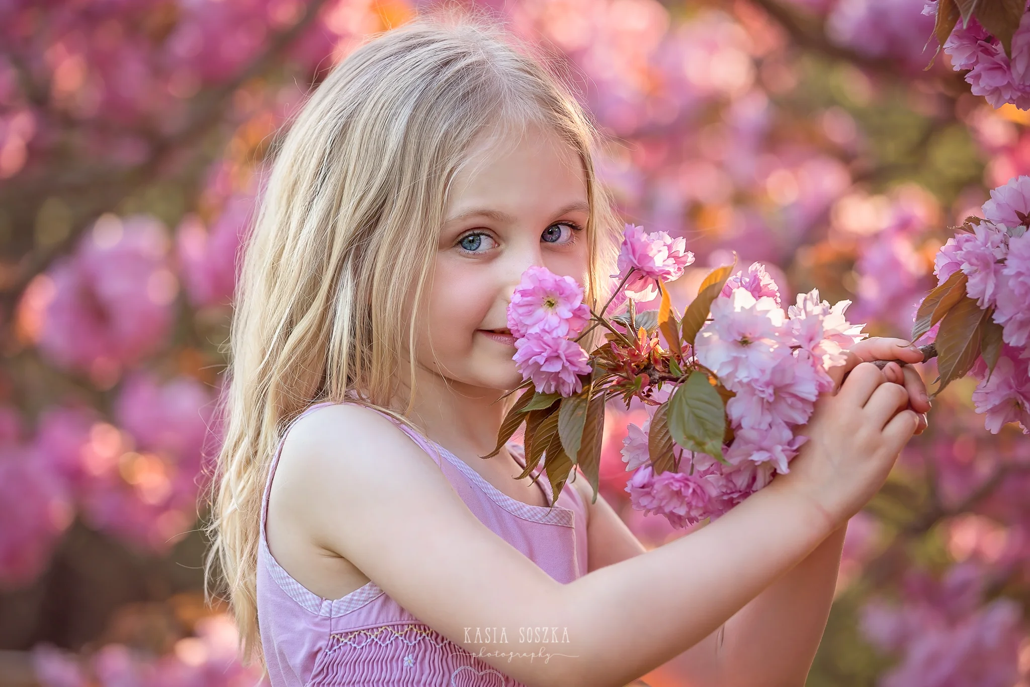 Leeds child photography Bradford child session York children photography: pretty little blond girl in a pink dress smelling cherry blossoms