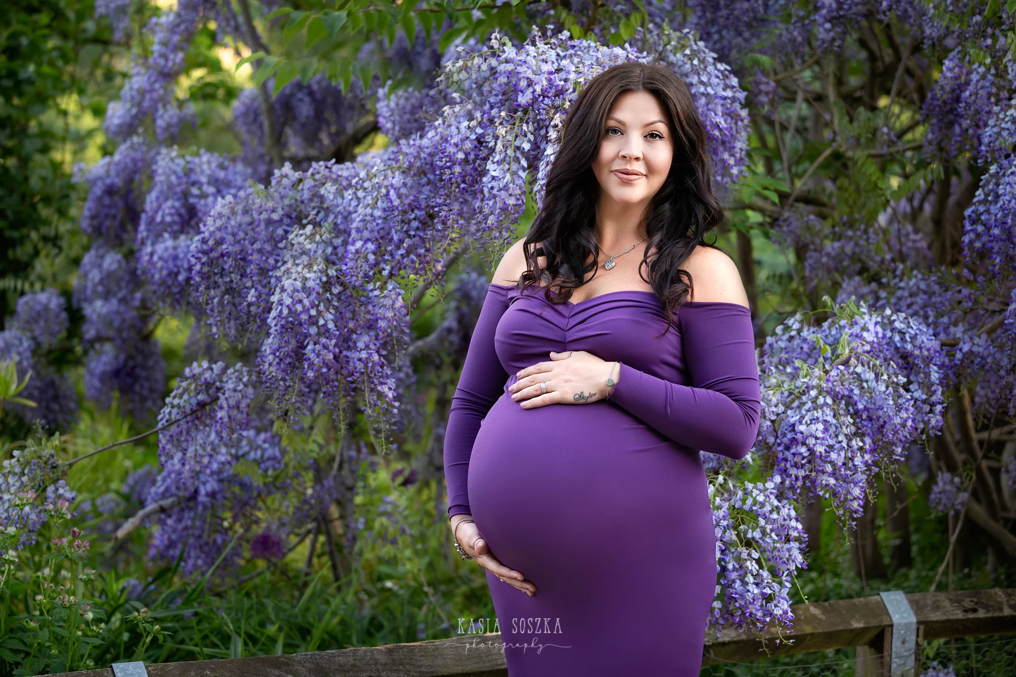 Leeds maternity photography Leeds Bradford York Harrogate maternity photographer: beautiful pregnant woman in a long purple dress posing for a maternity photo in a spring garden