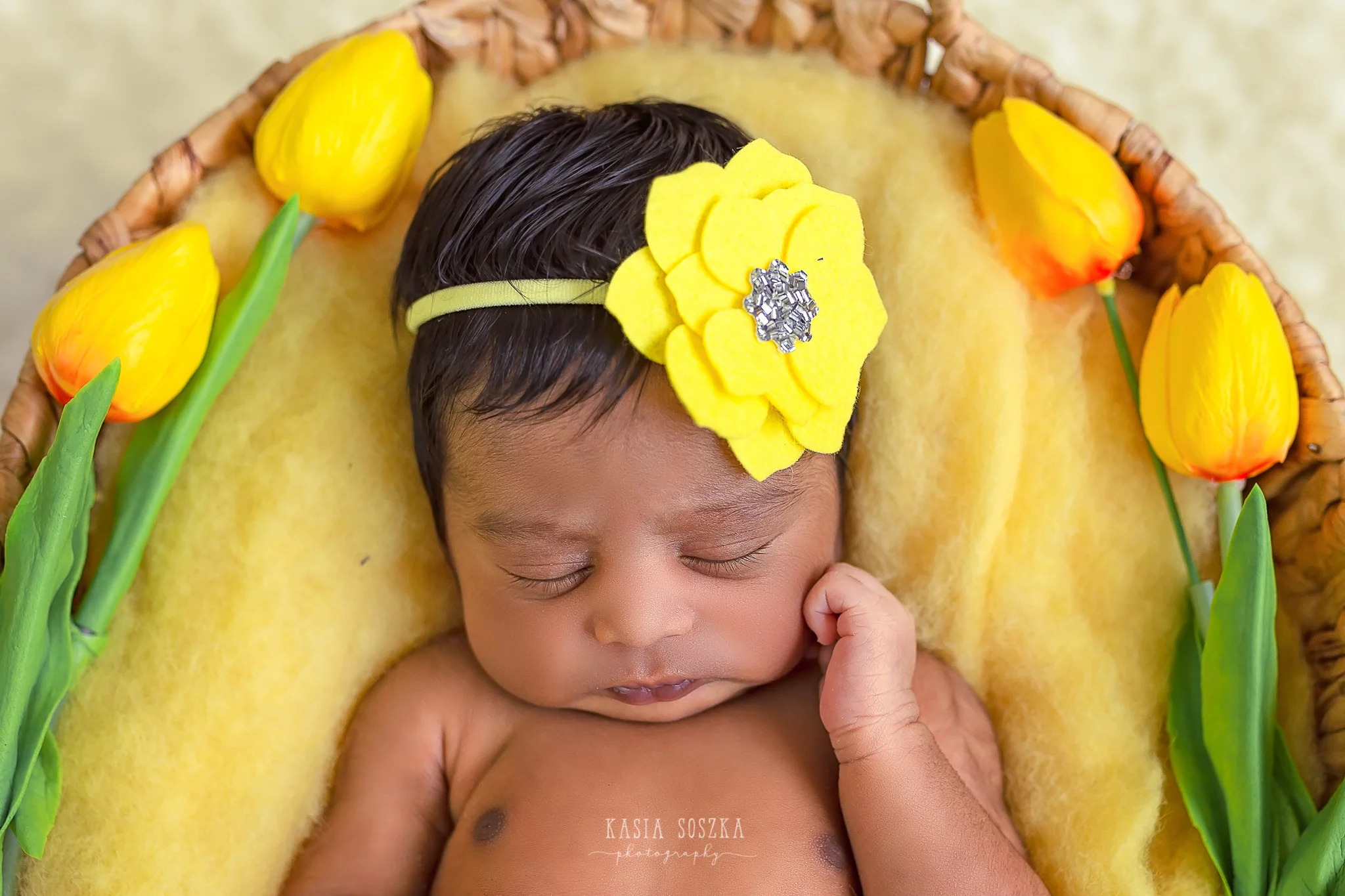 Newborn photography Leeds-Bradford-York-Harrogate: newborn baby girl sleeping on a yellow blanket surrounded by yellow tulips