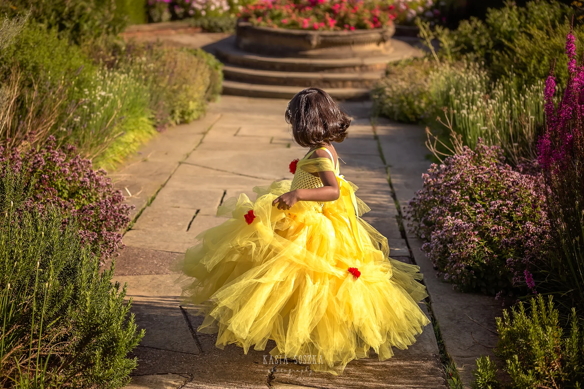Child photography Leeds, child outdoor princess session Leeds, Yorkshire: beautiful little girl in a yellow princess dress dancing in a garden
