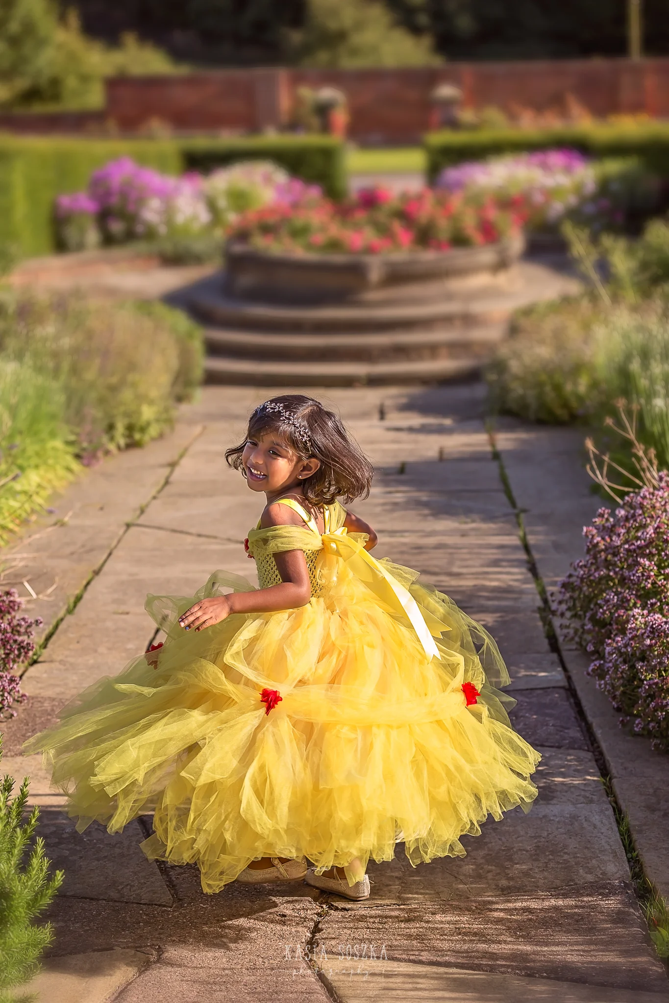 Child photography Leeds, child outdoor princess session Leeds, Yorkshire: beautiful little girl in a yellow princess dress dancing in a garden