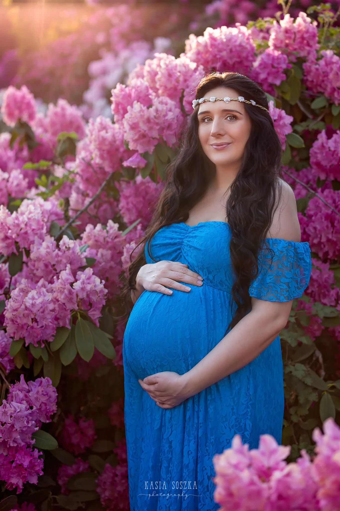 Maternity photography Leeds, Yorkshire, pregnancy session Leeds: beautiful pregnant woman with long black hair standing against a wall of flowers