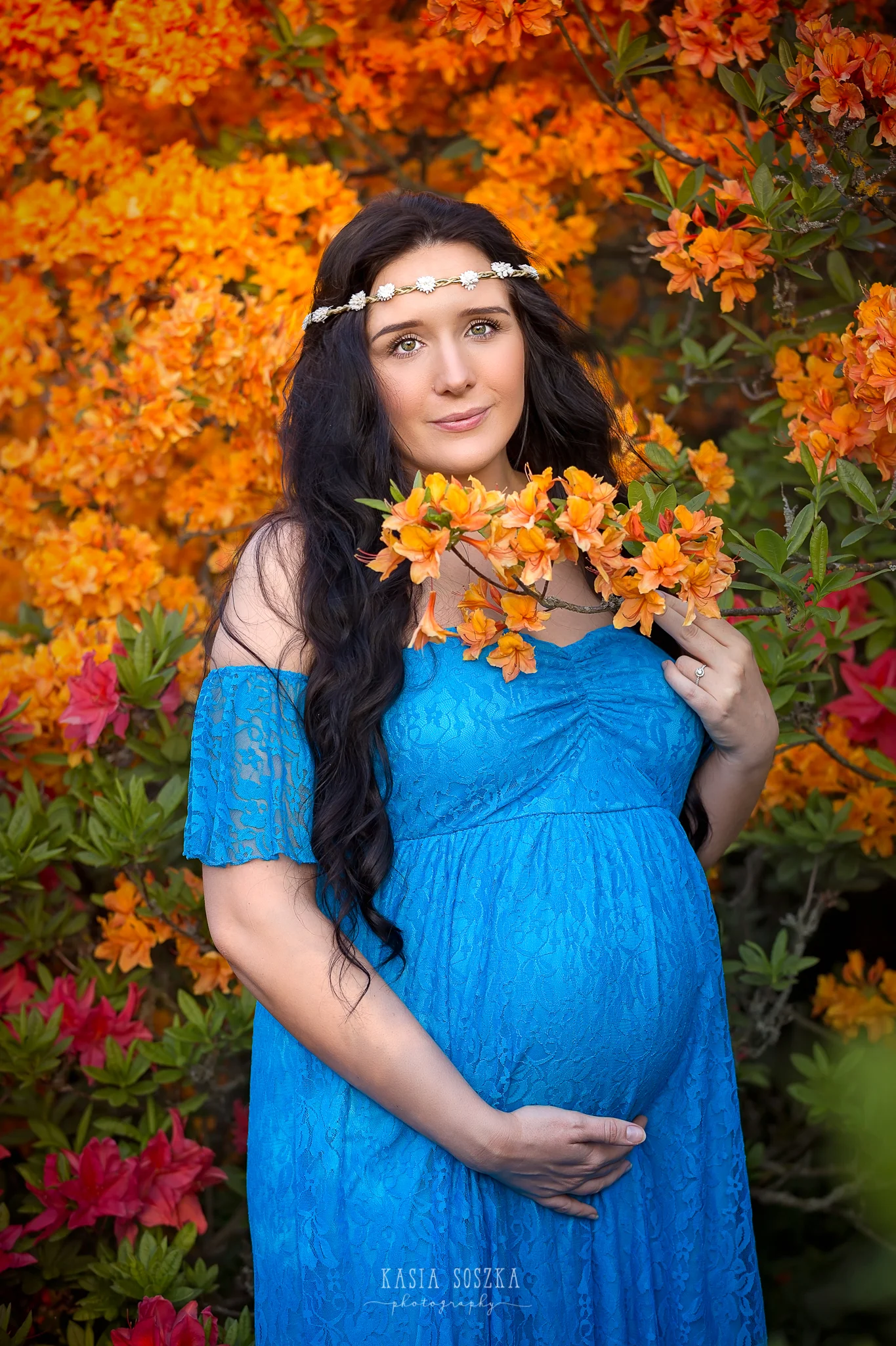 Maternity photography Leeds, Yorkshire, pregnancy session Leeds: beautiful pregnant woman with long black hair standing against a wall of flowers