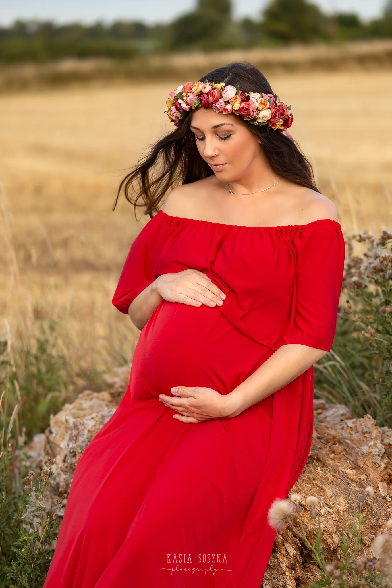 Maternity photography Yorkshire Leeds, Bradford, York, Harrogate, Wakefield: beautiful pregnant woman in red dress resting near wheat fields