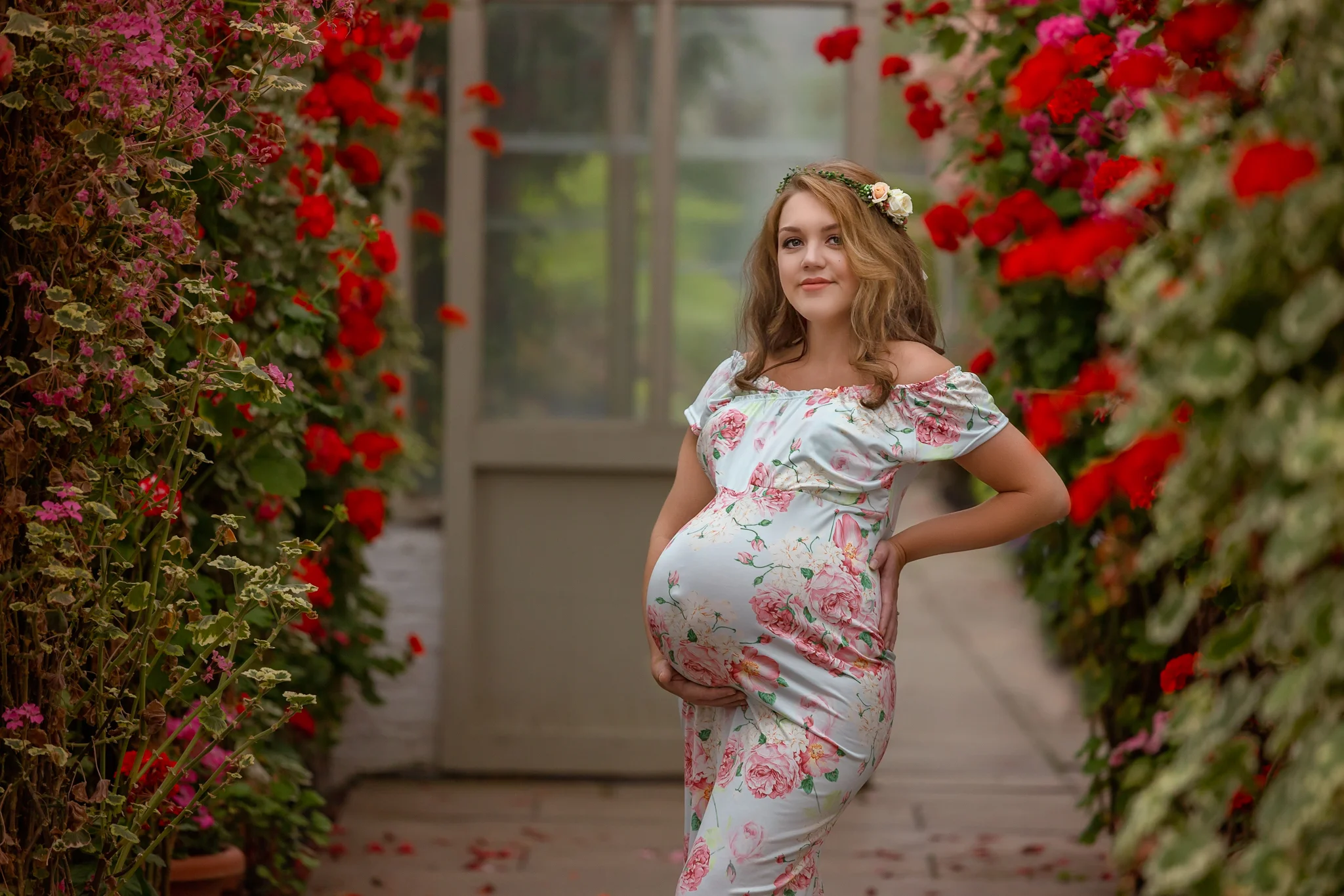 Maternity photography Leeds, Bradford, York, Harrogate: beautiful pregnant woman in a floral dress posing for a photo in a conservatory