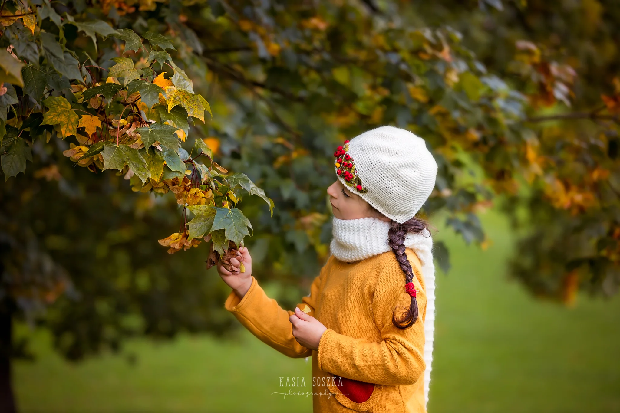 Child photography Leeds, Yorkshire: little girl in mustard yellow sweater looking at autumn leaves. Child autumn session in Leeds.