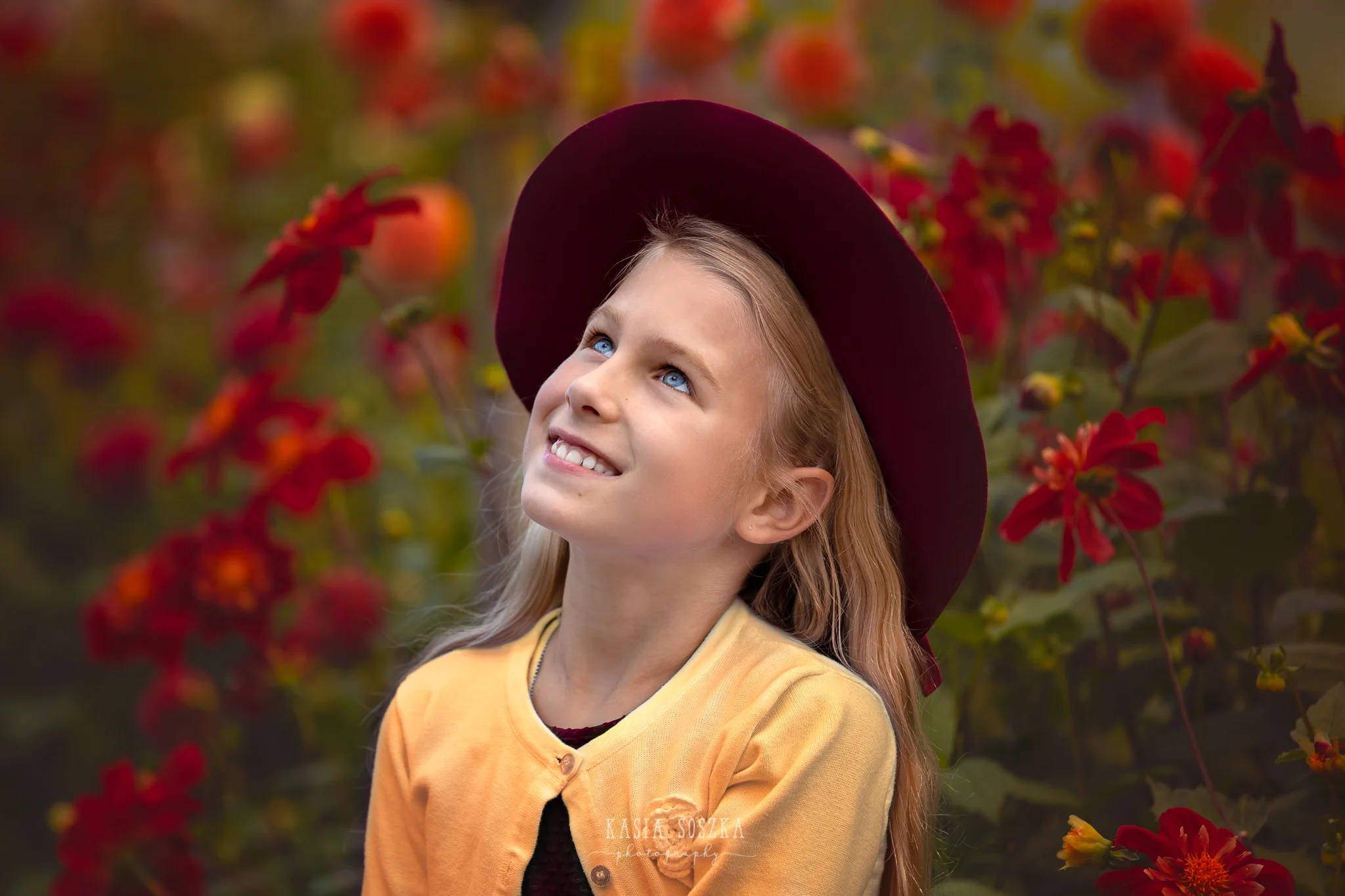 Children photography, child photographer Leeds, York, Bradford, Harrogate: pretty blond girl with blue eyes posing for a portrait against red autumn flowers
