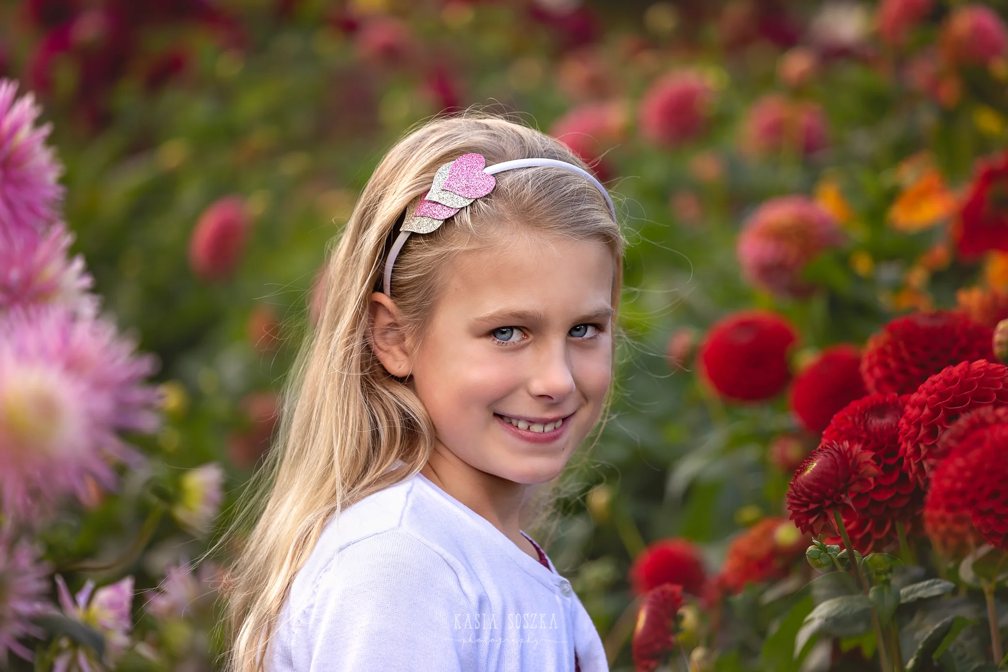 Children photography, child photographer Leeds, York, Bradford, Harrogate: pretty blond girl with blue eyes posing for a portrait against red autumn flowers