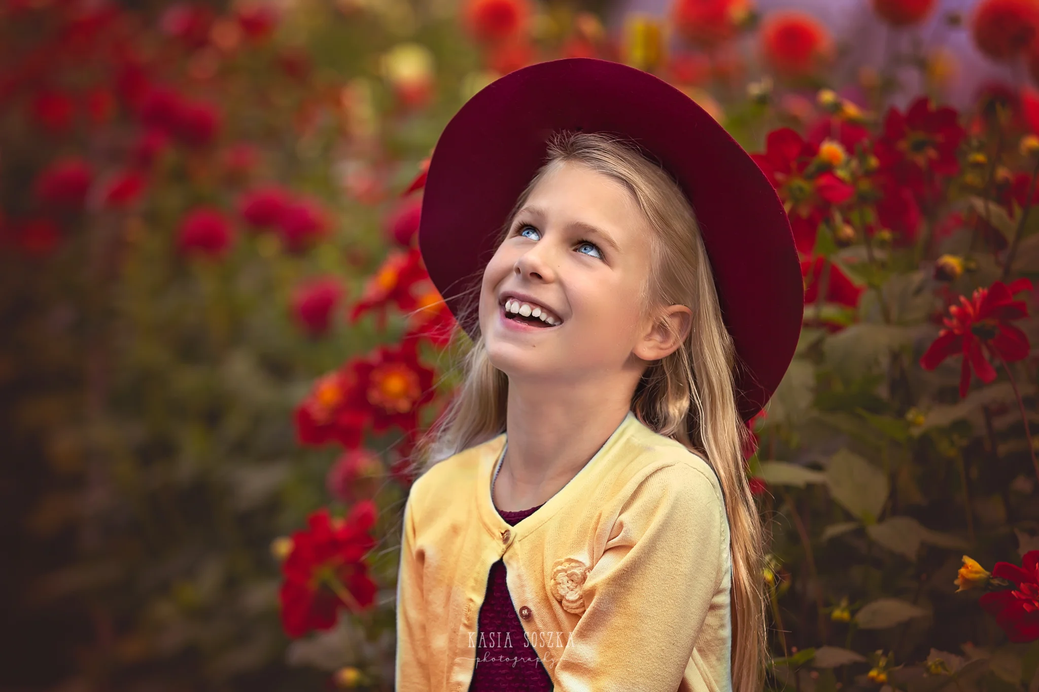 Children photography, child photographer Leeds, York, Bradford, Harrogate: pretty blond girl with blue eyes posing for a portrait against red autumn flowers