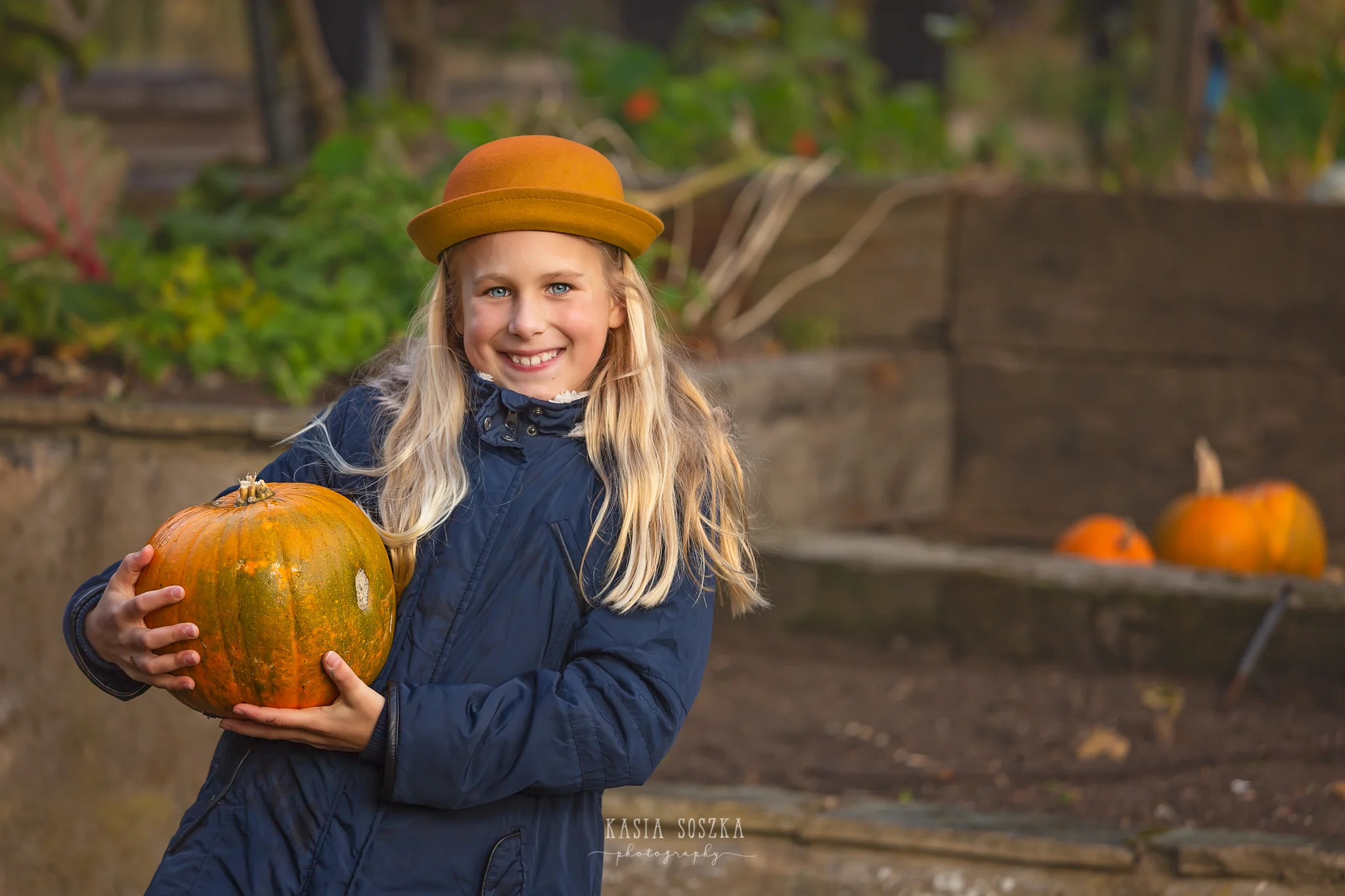 Children photography, child photographer Leeds, York, Bradford, Harrogate: pretty blond girl in a yellow hat holding a pumpkin