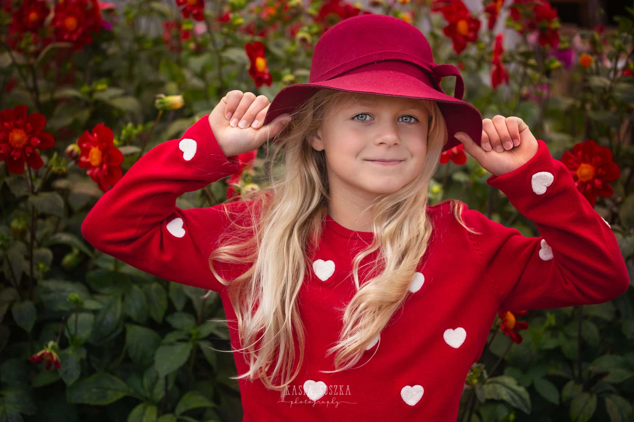 Children photography, child photographer Leeds, York, Bradford, Harrogate: pretty blond girl with blue eyes posing for a portrait against purple autumn flowers