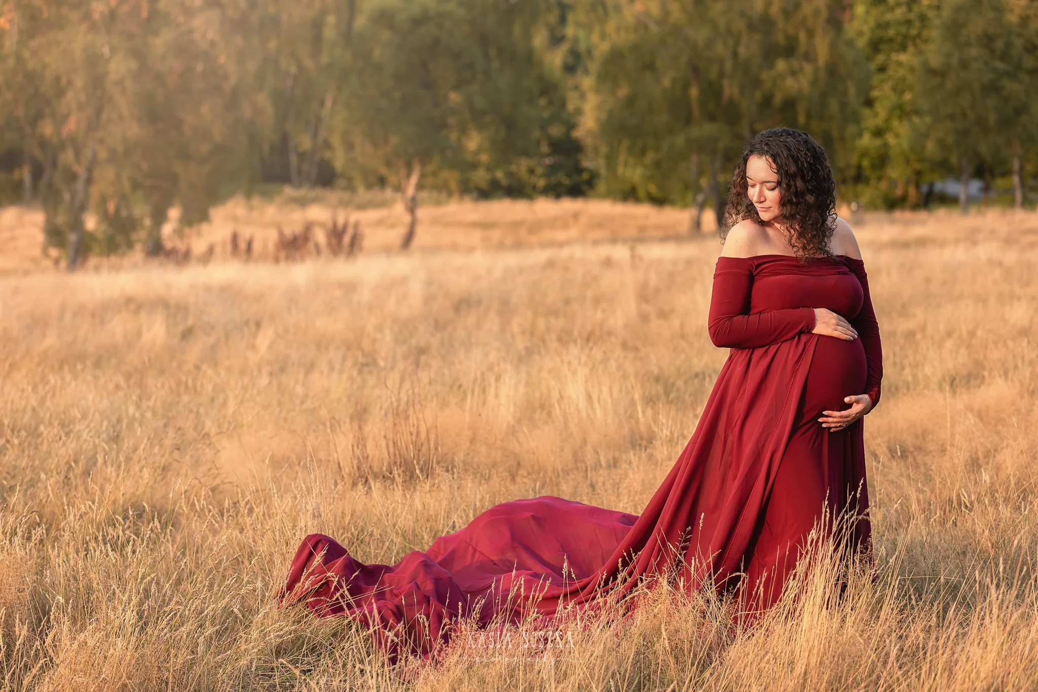 Maternity photography, maternity photographer Leeds , York, Harrogate, Bradford: woman in a long wine red dress posing for her pregnancy photos in a park in Leeds, Yorkshire, on a sunny autumn day