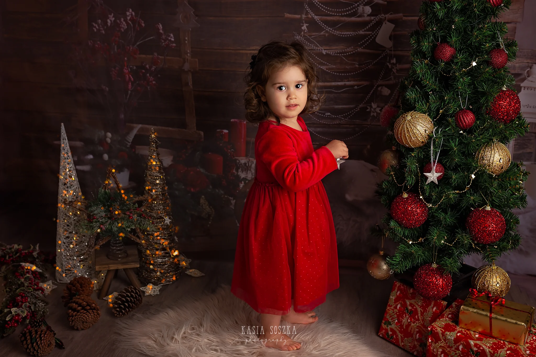 Child photographer Leeds, York, Bradford, Harrogate. Christmas Mini Sessions 2018 Leeds: beautiful little girl in a red dress decorating Christmas tree.
