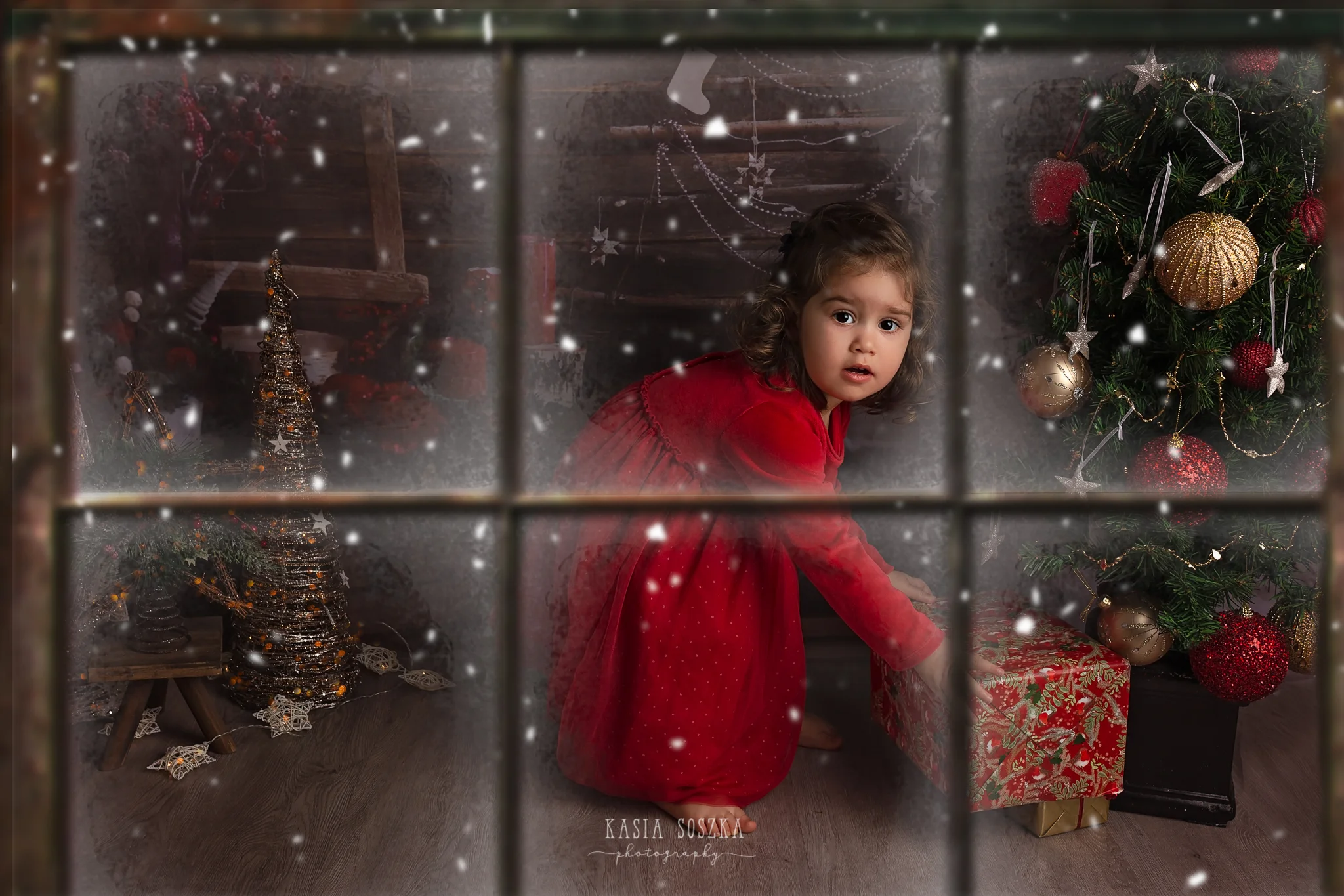 Child photographer Leeds, York, Bradford, Harrogate. Christmas Mini Sessions 2018 Leeds: beautiful little girl in a red dress checking presents under the Christmas tree.