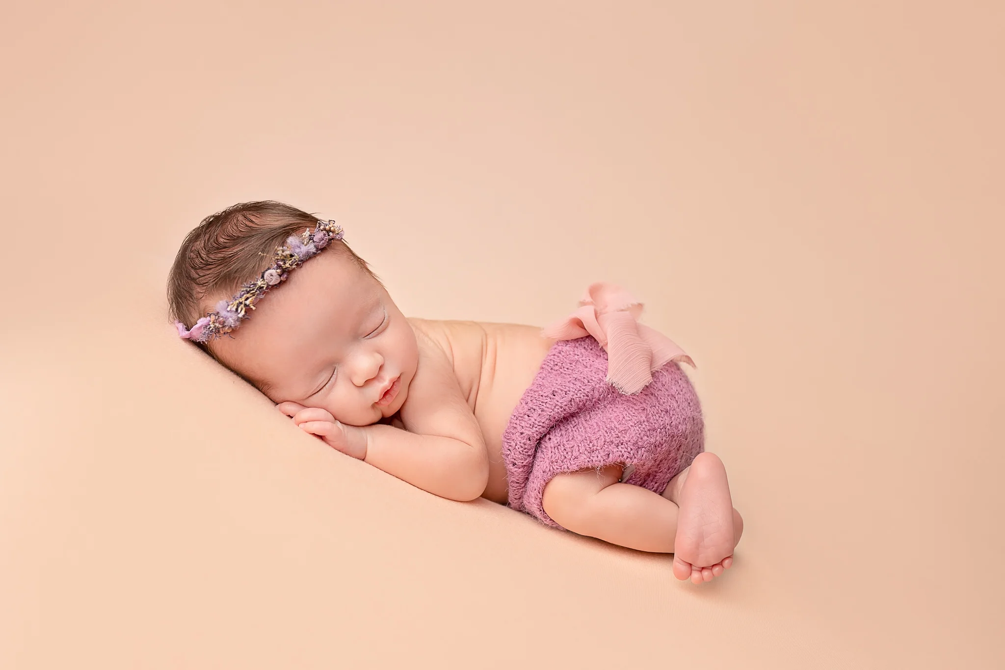Professional newborn photography Leeds-York-Bradford-Harrogate-Wakefield: newborn baby girl sleeping on a peach blanket during her newborn photoshoot in Leeds, Yorkshire
