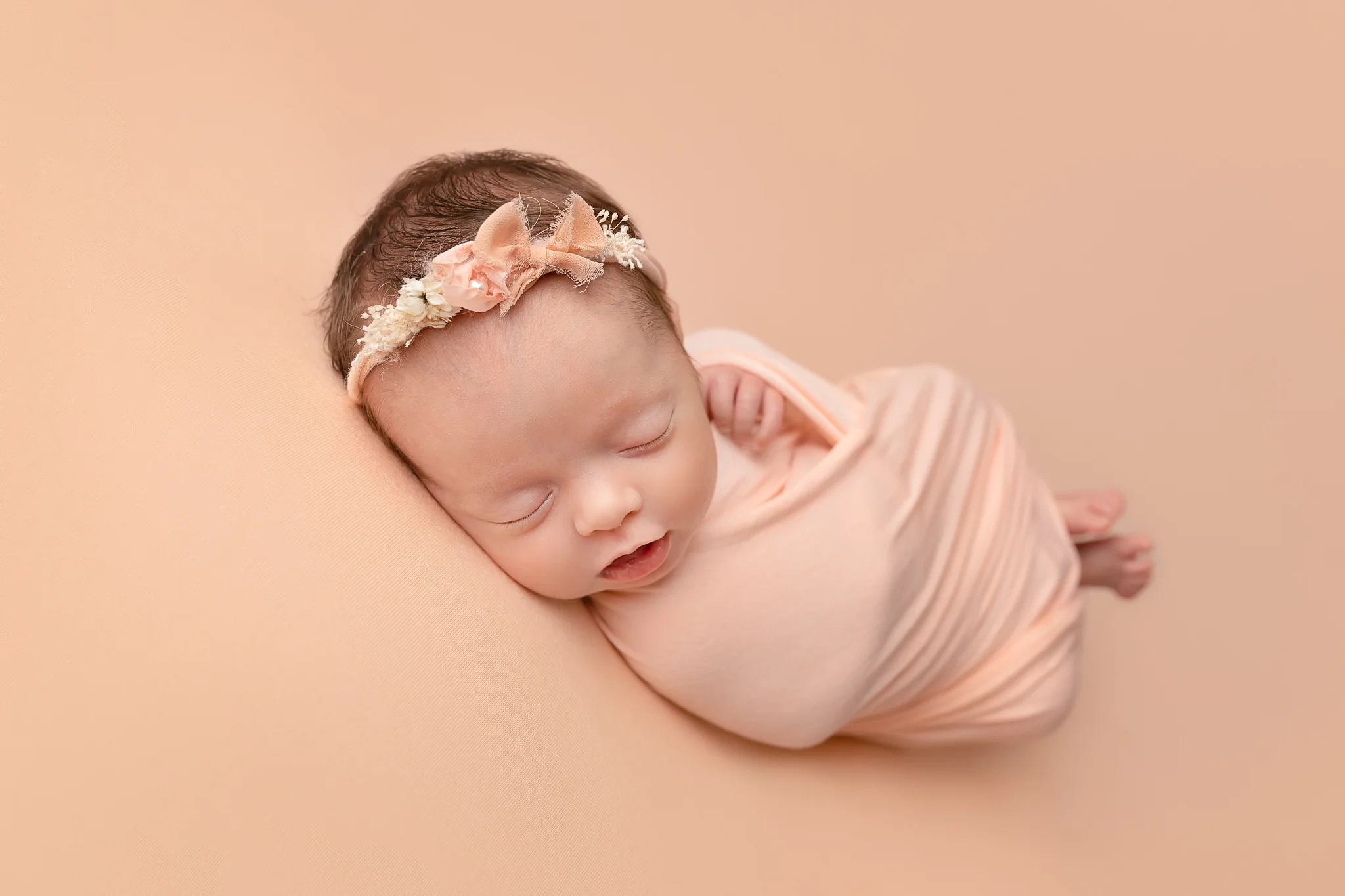 Professional newborn photography Leeds-York-Bradford-Harrogate-Wakefield: newborn baby girl sleeping on a peach blanket during her newborn photoshoot in Leeds, Yorkshire