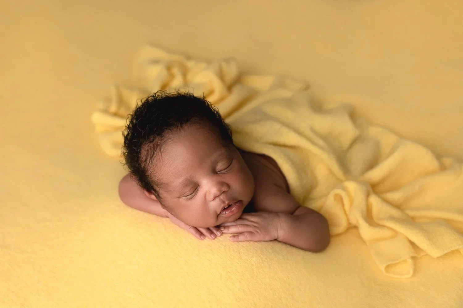 Newborn baby boy sleeping on his tummy on a yellow blanket