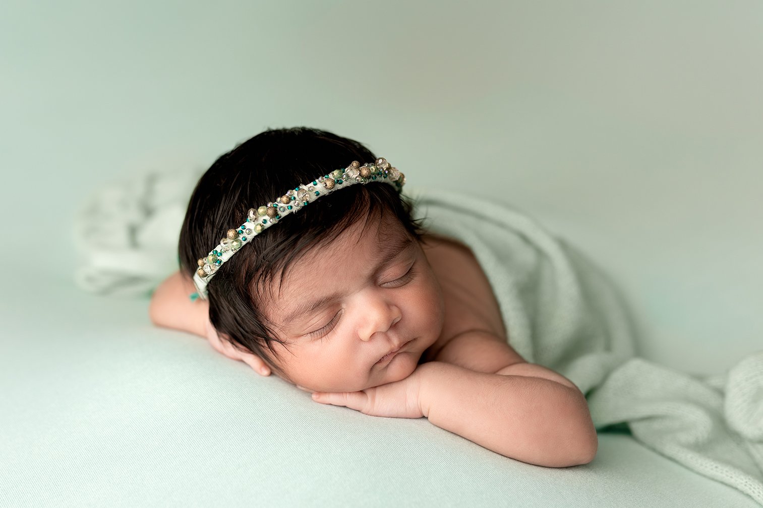 Newborn photography Leeds: newborn baby girl sleeping in a chin on hands pose on a sage green blanket during her newborn photoshoot in Leeds, Yorkshire