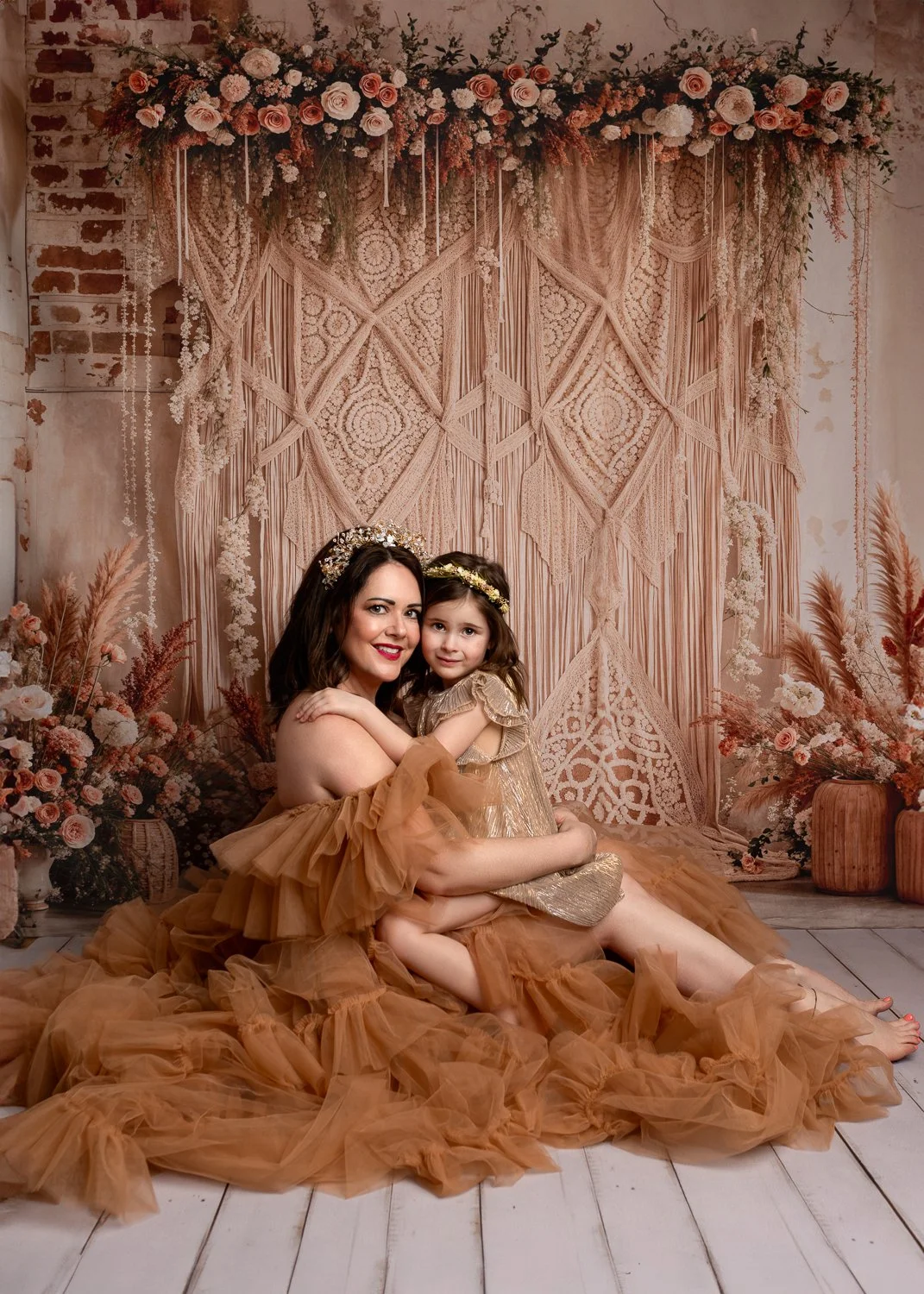 Mum dressed in a couture gown sitting on the floor, holding her daughter on her lap