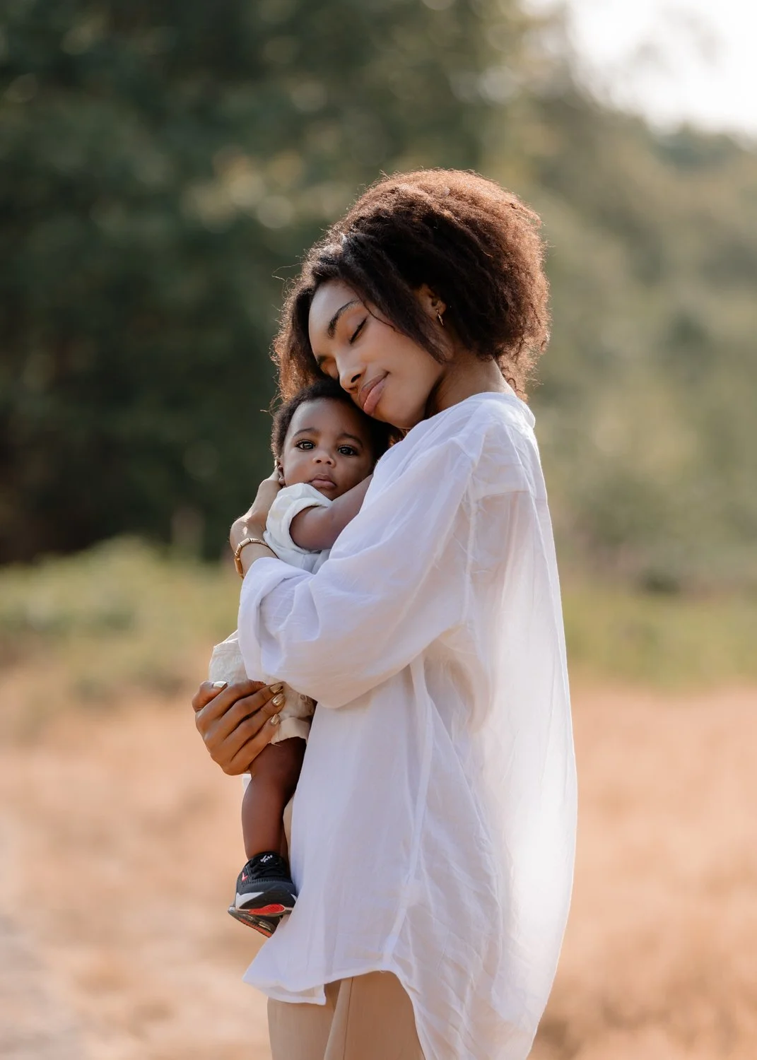 A young mother hugging her baby son on a sunny summer evening in Leeds
